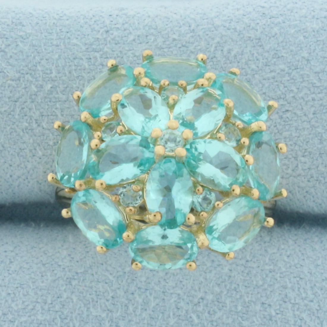 Blue Tourmaline Flower Ring in 10k Yellow Gold: In 10k yellow gold. 20mm wide at top center. Contains high quality Tourmaline gemstones: 8-oval cut 6x4mm each, 5-oval cut 6x3.7mm each, 6-2.5mm each. All with beautiful aqua color and excellent clari