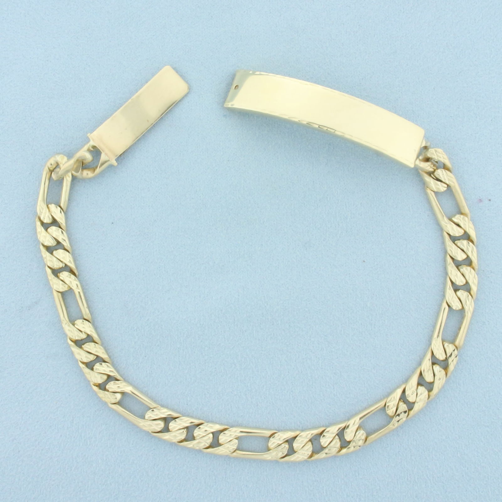 Mens Figaro Name Plate ID Bracelet in 10k Yellow Gold: In 10k yellow gold. 10 1/2 inches long and 3/8 inch wide (at widest point). Engravable plate is 2 inches long. Hidden slide closure (press pin in hole to release clasp). 36.4g.