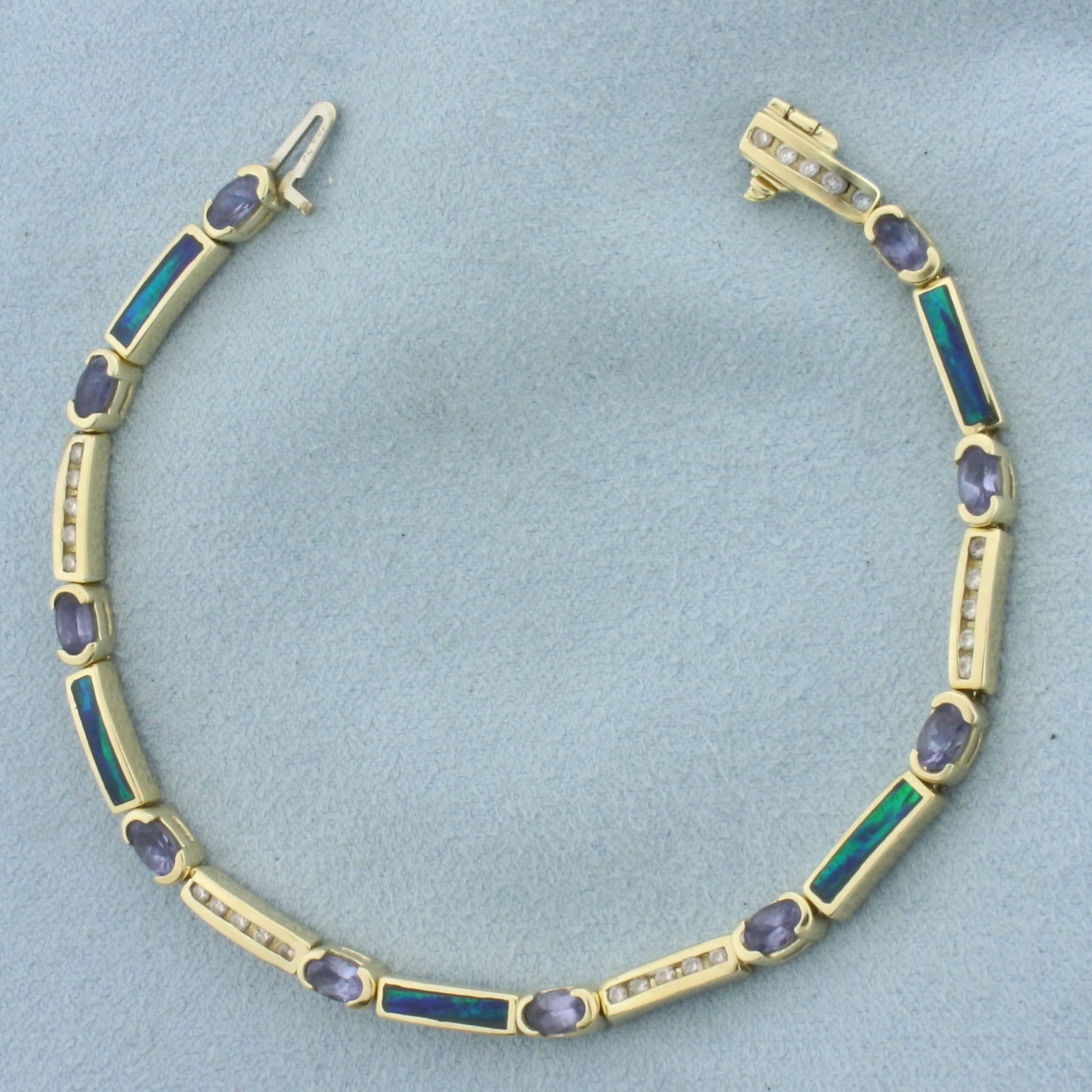 Tanzanite, Diamond, and Opal Inlay Bracelet in 14k Yellow Gold: In 14k Yellow Gold. Contains ten 3x5mm high quality natural Tanzanite gemstones, approximately 2.5ct TW, with vibrant color and excellent clarity. Also contains five 10mm high quality natural black Op