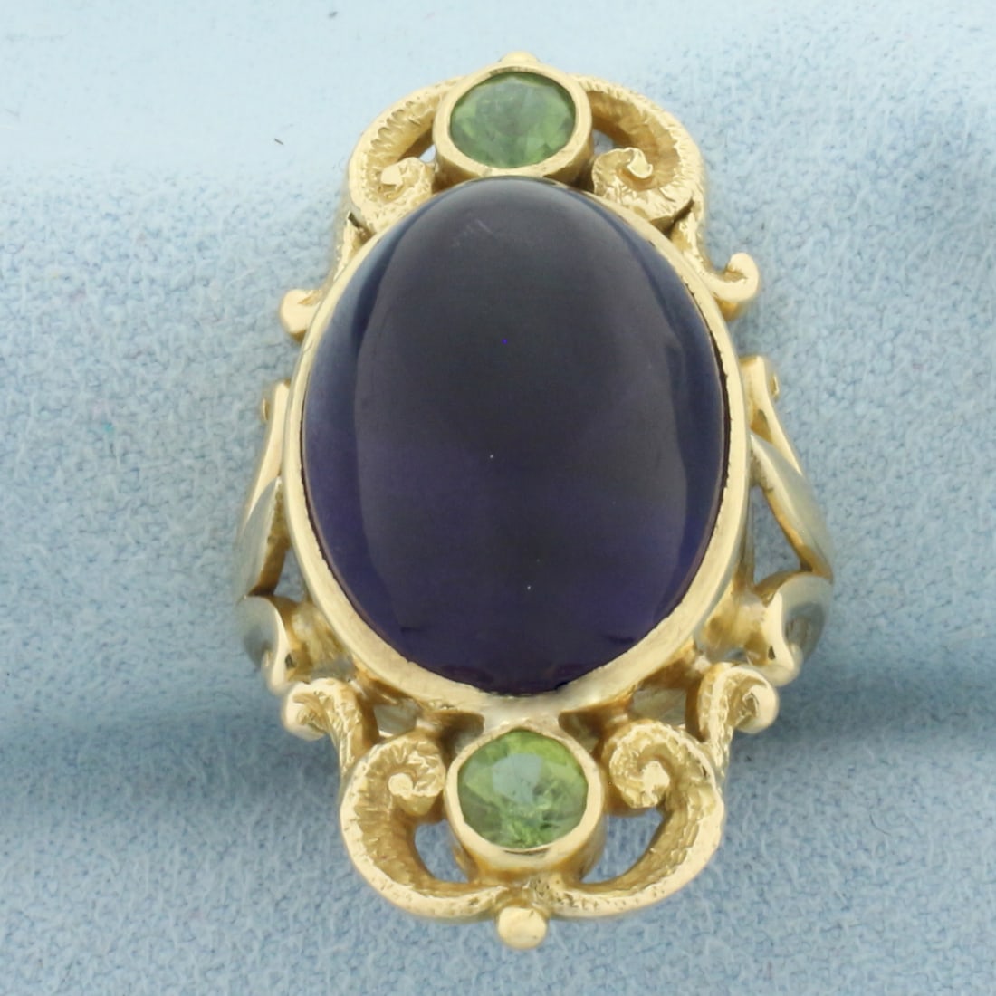 Vintage Amethyst and Peridot Statement Ring in 14k Yellow Gold: In 14k Yellow Gold. Contains one 19x14mm high quality oval cabochon natural Amethyst gemstone with intense color and excellent clarity. Also contains two 4.5mm high quality natural Peridot gemstones w