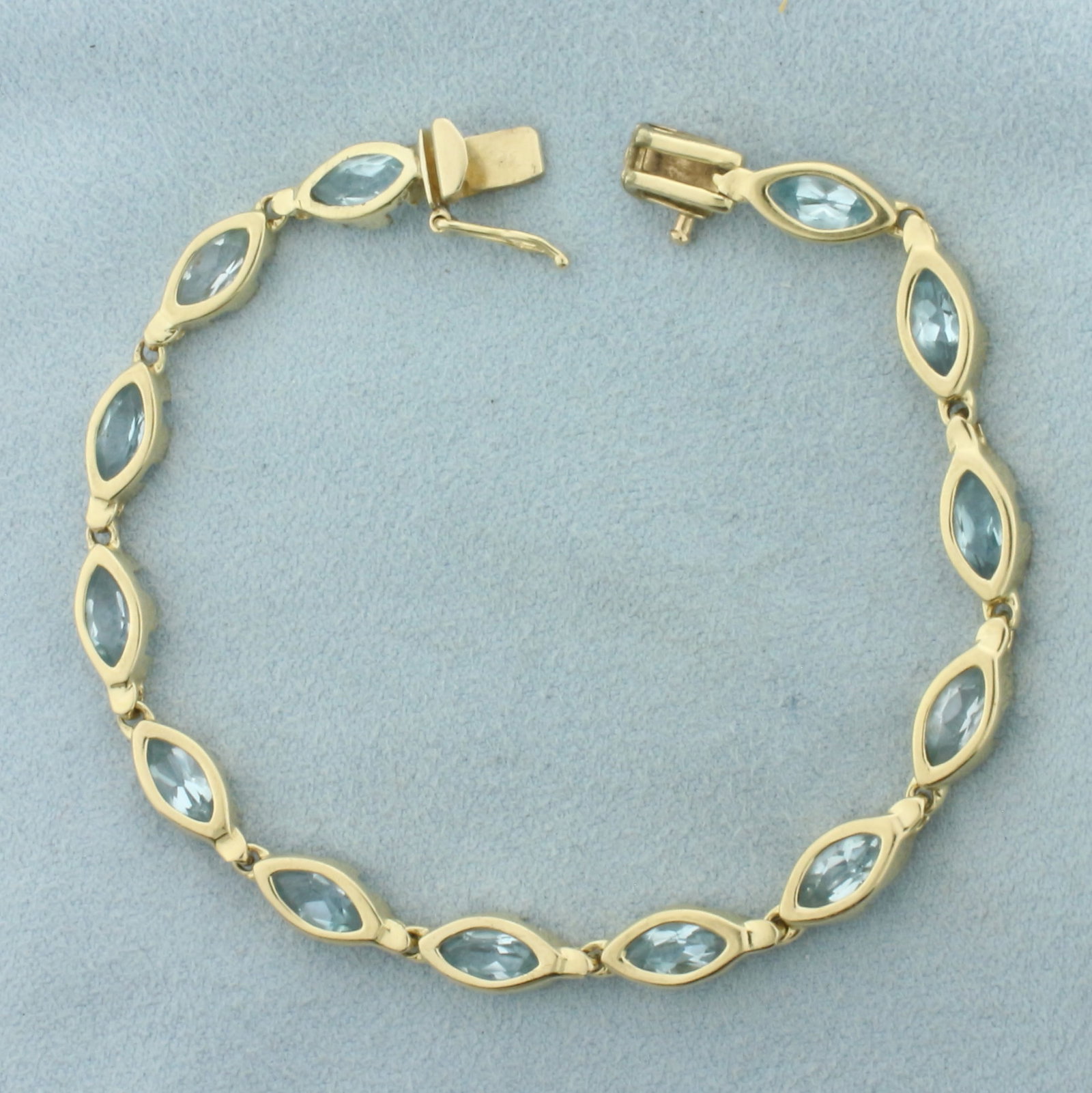 Sky Blue Topaz Tennis Bracelet in 14k Yellow Gold: In 14k Yellow Gold. Contains thirteen 7x3.5mm high quality Sky Blue Topaz gemstones with bright color and excellent clarity. 7 inches long. 5.3mm wide. Slide clasp with safety latch. 10.2g.