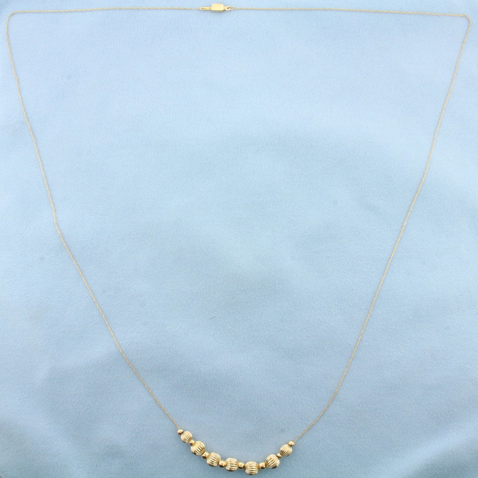 26 Inch Gold Ball Bead Necklace in 14k Yellow Gold: In 14k Yellow Gold. Contains 2.3mm and 5.2mm gold ball beads. Cable link chain 26 inches long chain. 0.4mm wide. Slide clasp. 1.7g.