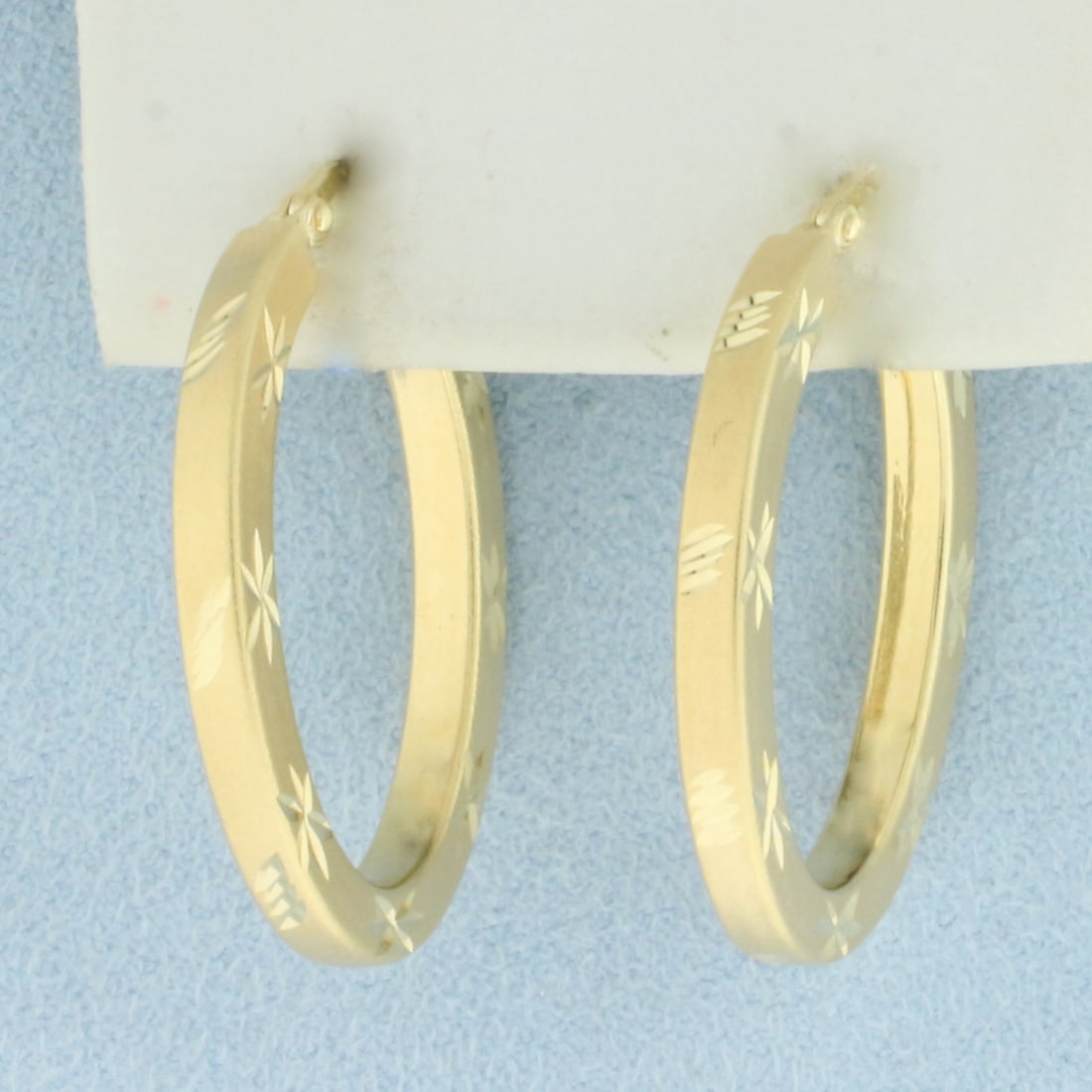 Diamond Cut Oval Hoop Earrings in 14k Yellow Gold: In 14k Yellow Gold. 1 1/4 inches long. 7/8 inch wide. 3mm thick. Diamond cut design. Leverback. 4.1g.