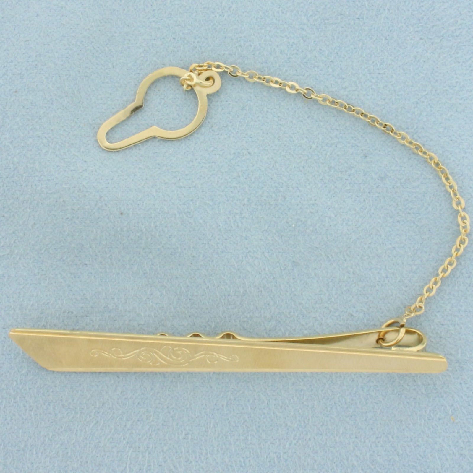 Vintage Engraved Tie Bar Clip with Chain in 18k Yellow Gold: In 18k yellow gold. 2 1/2 inches long x 5/16 inches wide (main clip piece). Unusual brushed finish for unique reflection of light and scroll engraved design. 6.7g.
