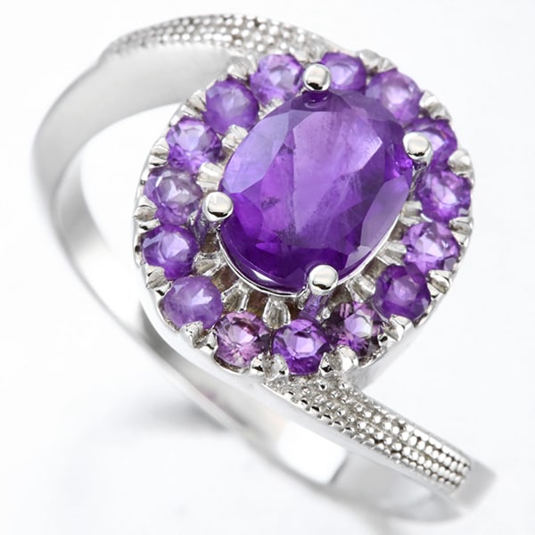 Amethyst Halo Ring in Sterling Silver: In platinum over .925 sterling silver. Contains one large deep purple amethyst gemstone, 1.2cts, surrounded by a halo of fifteen amethyst gemstones, 0.5ctw. Size 7. 3.7g