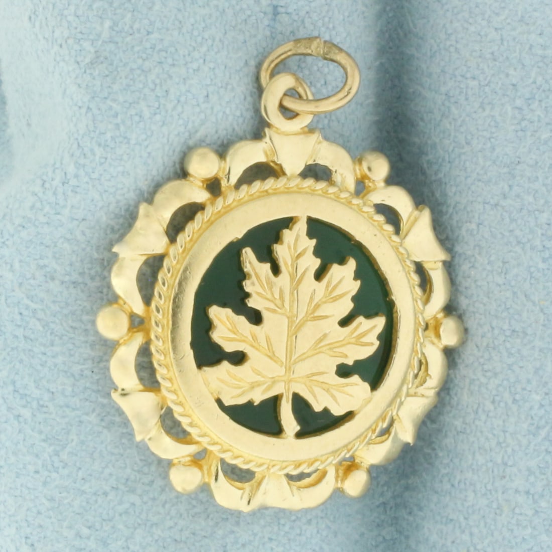 Nature Leaf Jade Charm in 14k Yellow Gold: In 14k Yellow Gold. Contains one 14mm high quality Jade gemstone with vibrant color and excellent clarity. 1 1/8 inch long. 7/8 inch wide.