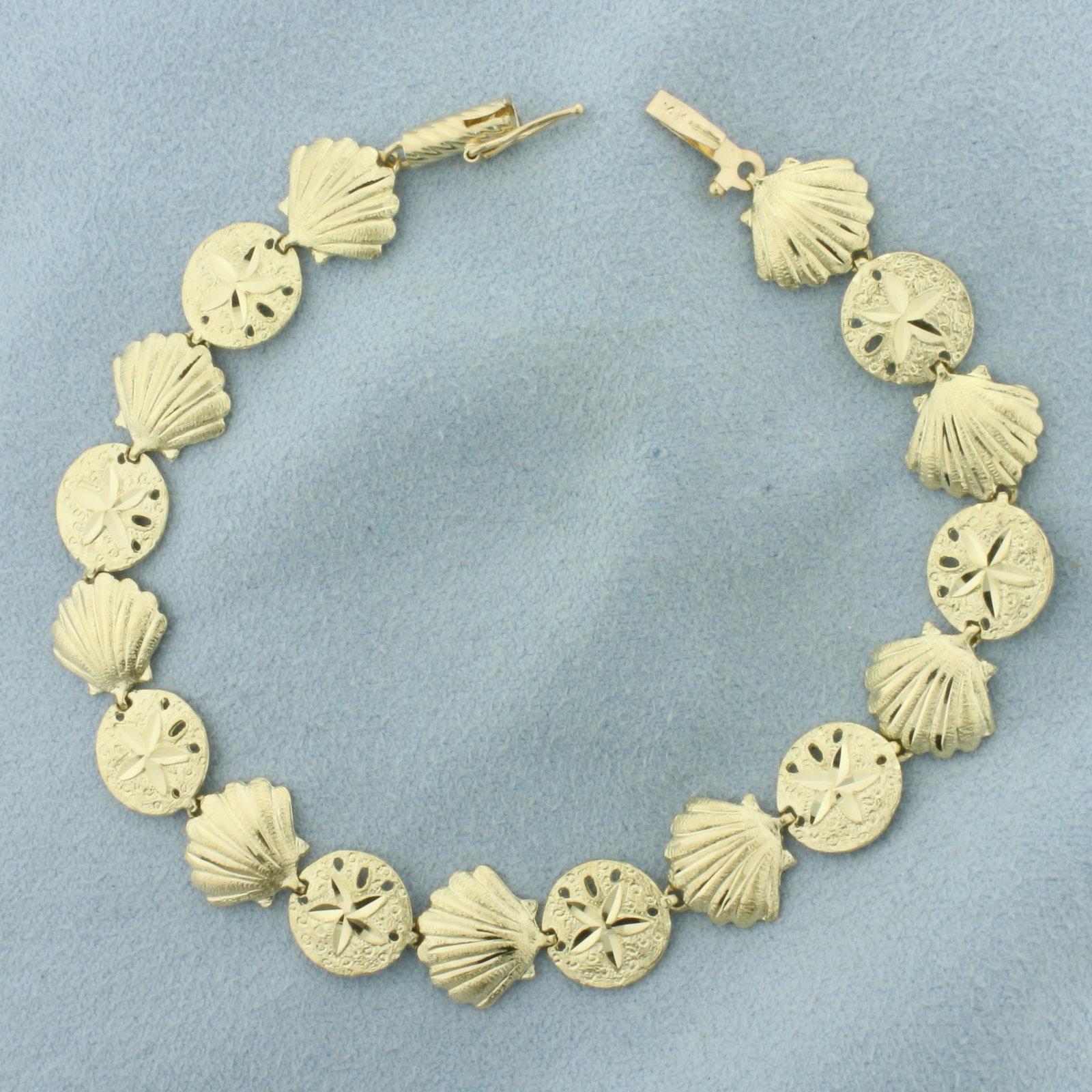 Sea Life Seashell and Sand Dollar Bracelet in 14k Yellow Gold: In 14k Yellow Gold. 7 1/8 inches long. 3/8 inch wide. Diamond cut for added sparkle. Barrel clasp with safety latch. 7.0g.