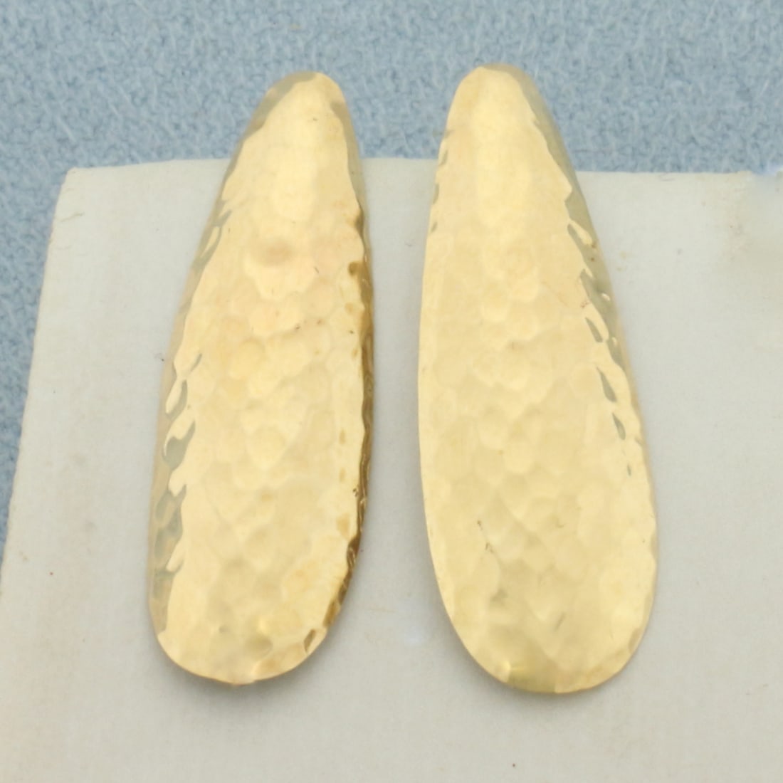 Hammer Finish Earrings in 14k Yellow Gold: In 14k Yellow Gold. 1 1/8 inch long. 3/8 inch wide at widest. Friction backs. 1.2g.