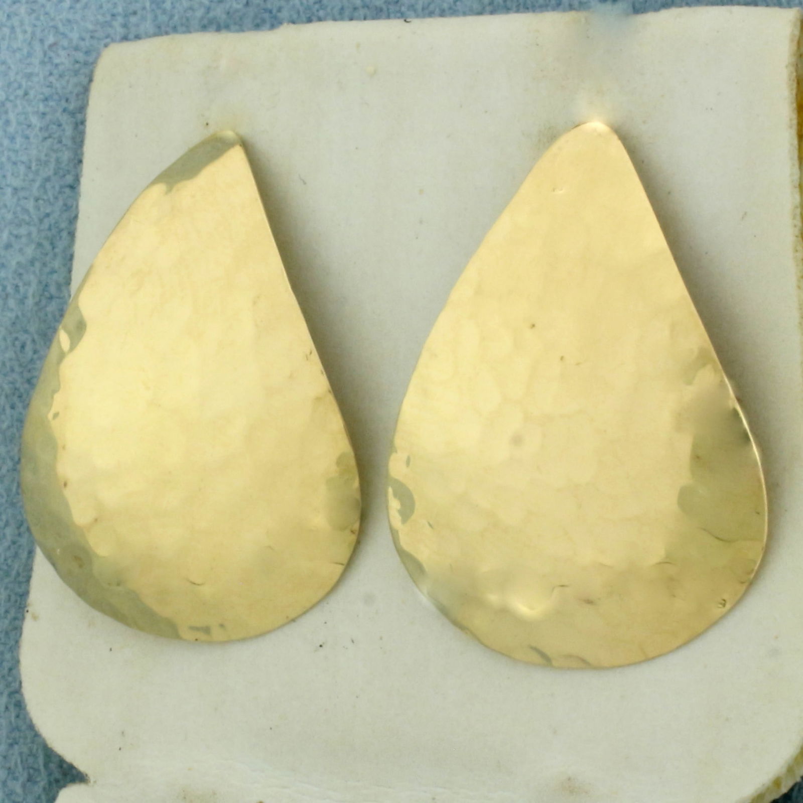 Teardrop Hammered Finish Earrings in 14k Yellow Gold: In 14k Yellow Gold. 1 inch long. 3/4 inch wide. Friction backs. 2.4g.