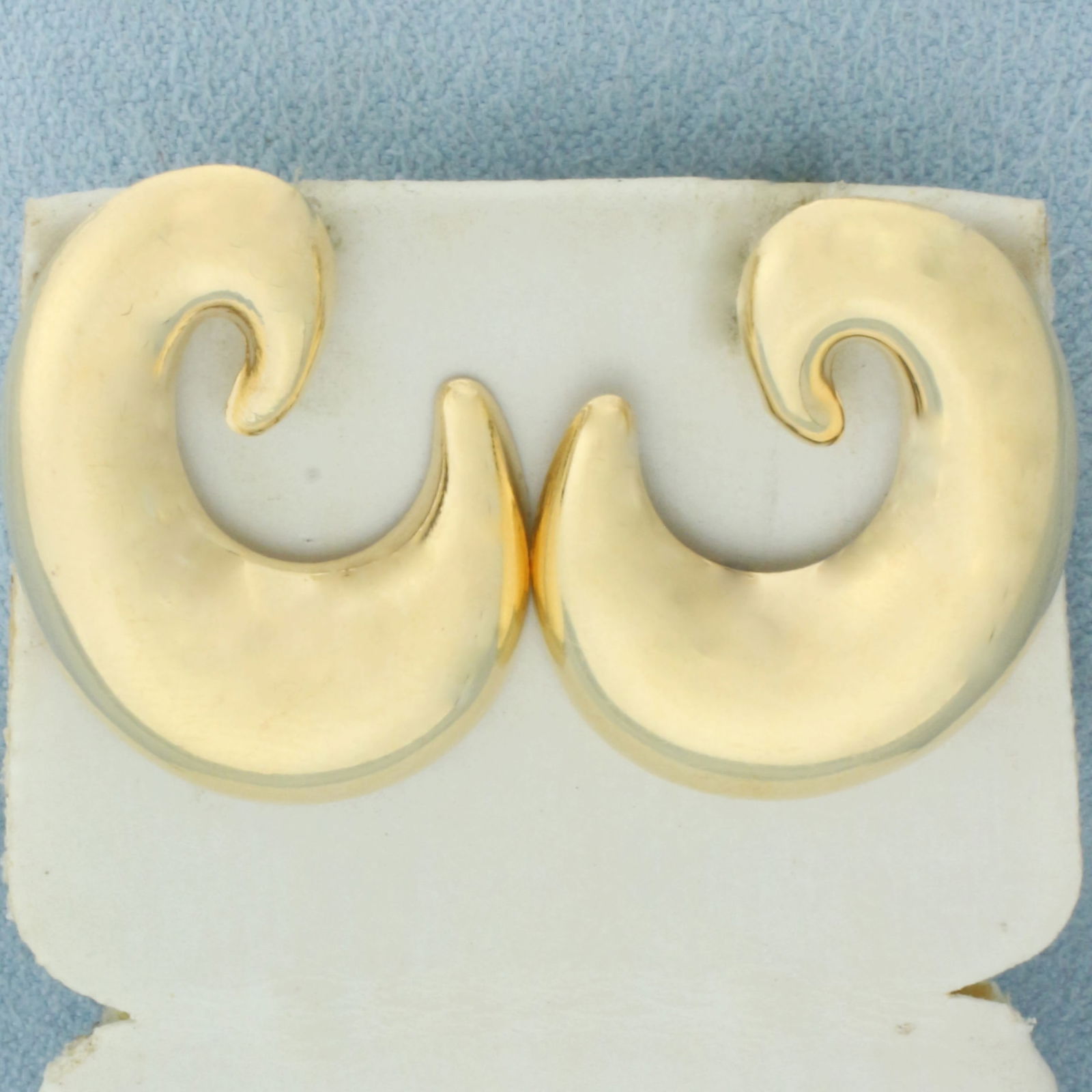 Swirl Design Earrings in 14k Yellow Gold: In 14k Yellow Gold. 1 1/8 inch long. 7/8 inch wide. Friction backs. 2.6g.