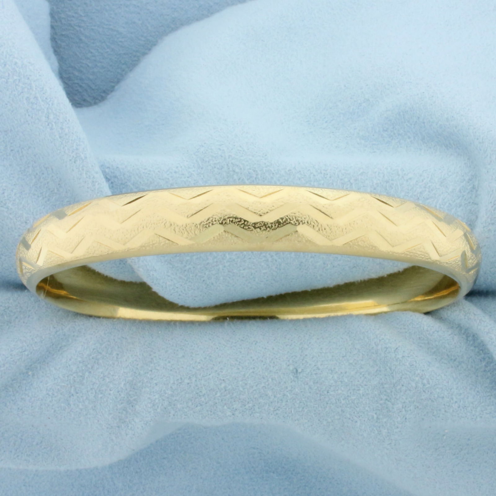 Wave Design Hinged Bangle Bracelet in 14k Yellow Gold: 14k yellow gold. 2 1/4 inch inner diameter. 8mm wide. Reflective and textured wave design for unique look. 13.1g.