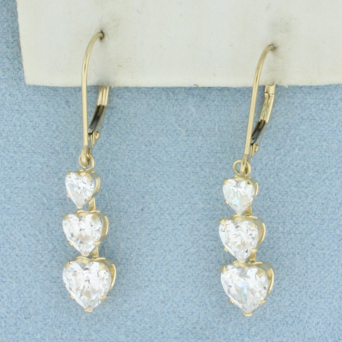 Heart Dangle CZ Earrings in 14k Yellow Gold: In 14k Yellow Gold. Contains two 6mm, two 5mm, and two 3.75mm high quality heart shaped CZ gemstones with excellent cut and clarity for added brilliance. 1 1/4 inch long. 1/4 inch wide. 2.3g.