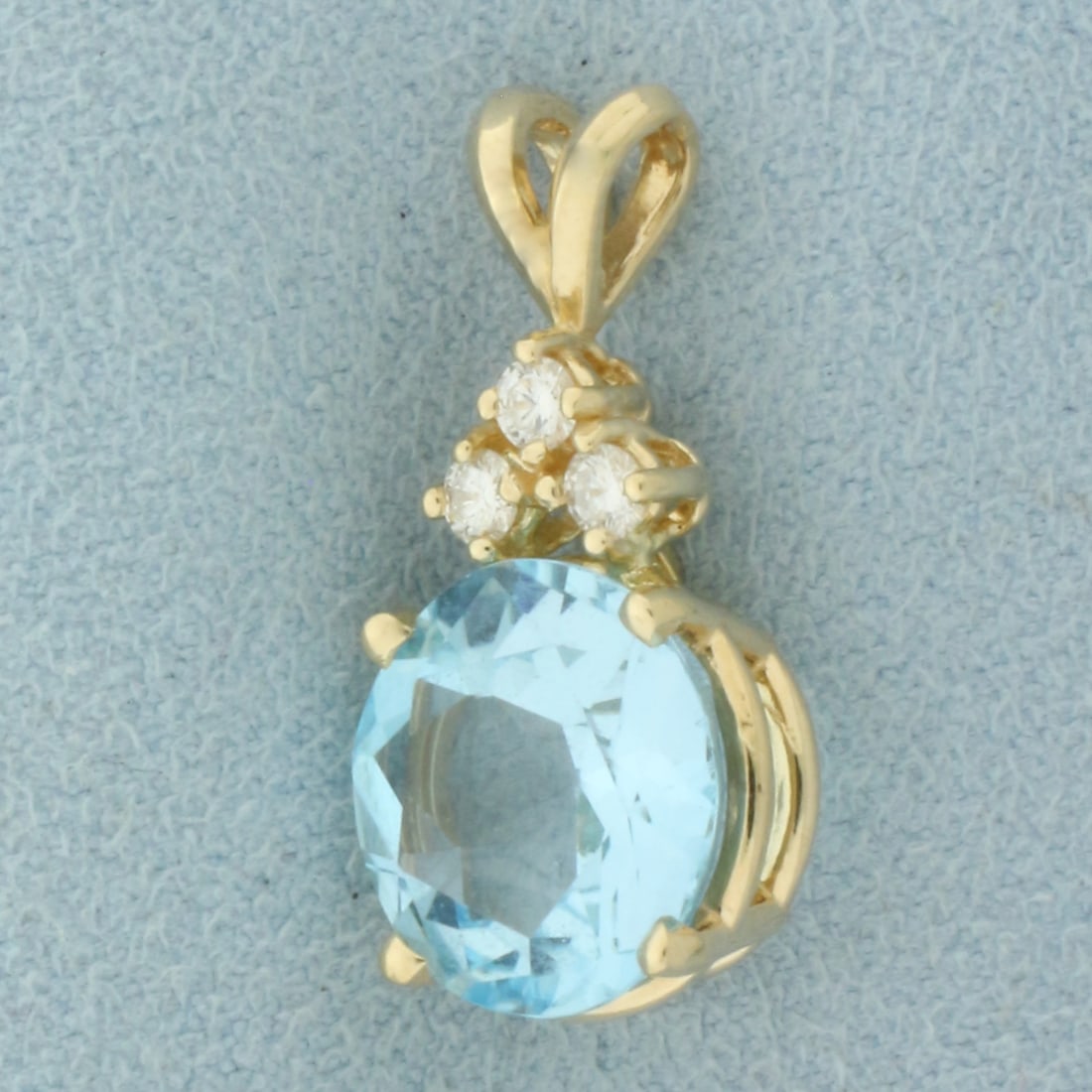 Blue Topaz and Diamond Pendant in 14k Yellow Gold: In 14k Yellow Gold. Contains one high quality 12mm natural Blue Topaz gemstone, approximately 6ct, with intense color and excellent clarity. Also contains three high quality .06ct diamonds, VS clarity