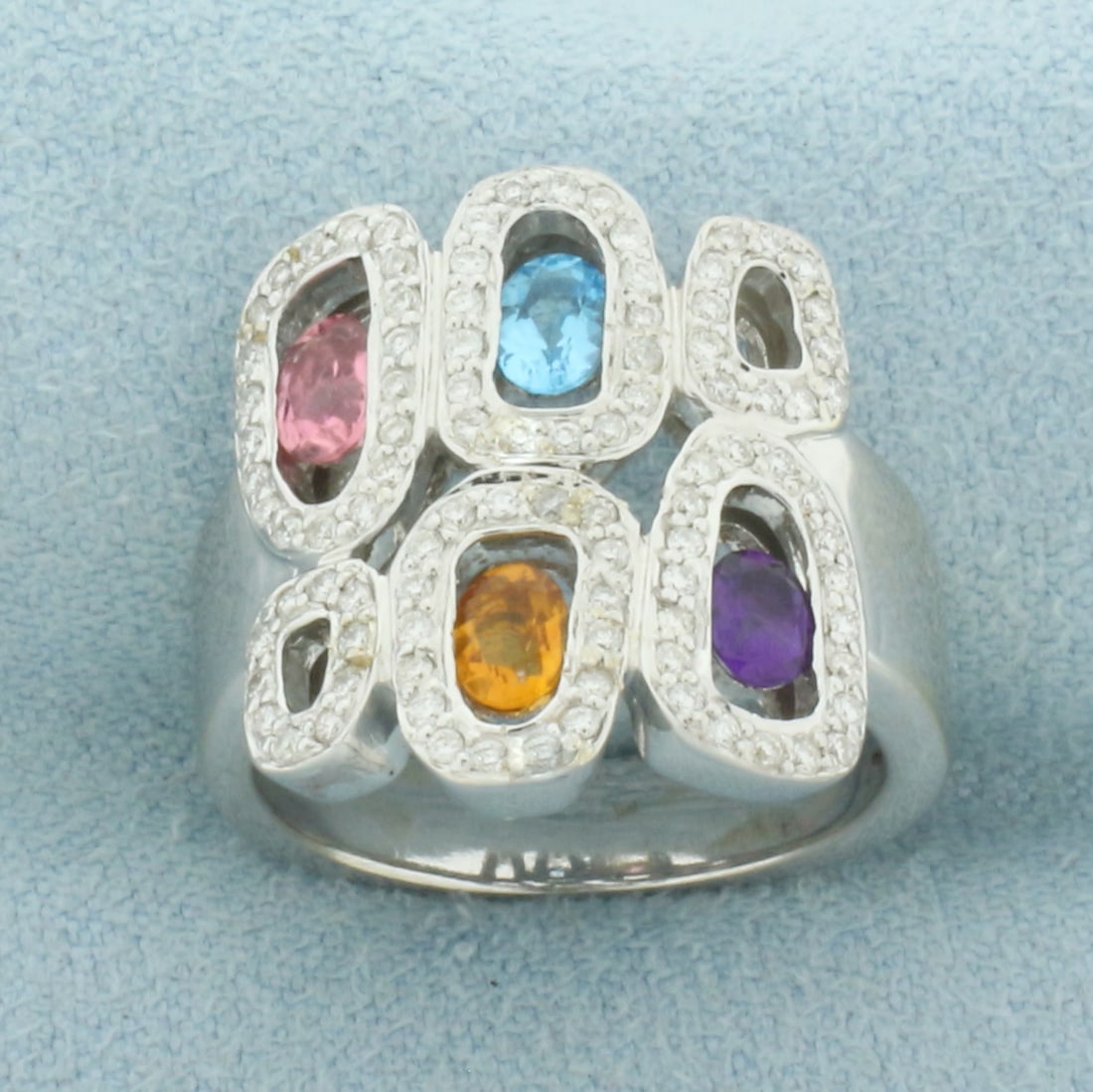 Rainbow Gemstone and Diamond Halo Ring in 18k White Gold: In 18k White Gold. Contains ninety-seven high quality 1/2pt diamonds. Also contains one 5mm Amethyst, one 4.5mm Blue Topaz, one 4.25mm Citrine, and one 4.5mm Pink Tourmaline gemstone, all high quality