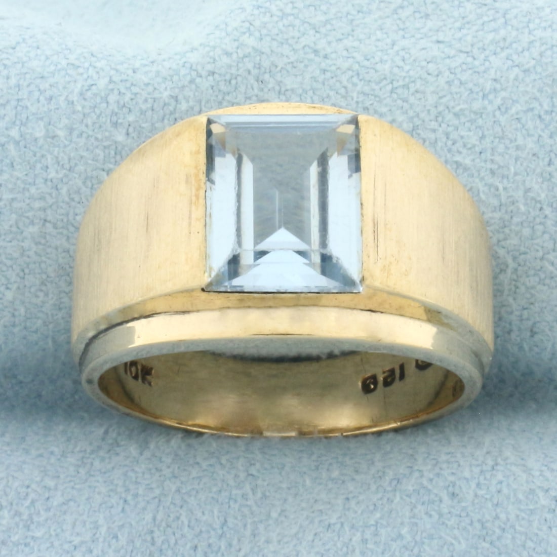 Mens Blue Topaz Statement Ring in 10k Yellow Gold: In 10k yellow gold. Contains one emerald cut 10mm by 8mm Blue Topaz gemstone, approximately 3cts, with excellent clarity and bright color. 13.5mm wide at center of ring. 7.4g. Size 9.5.