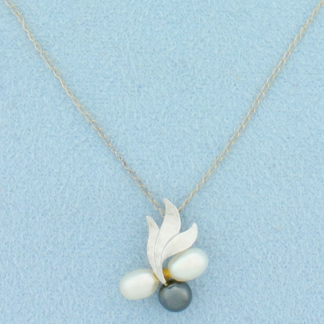 Pearl Flower Design Necklace in 14k White Gold: In 14k White Gold. Contains two 6mm white oval and one 5mm Tahitian Black Pearl, all high quality with high luster. Pendant is 5/8 inch by 1/2 inch. Chain is 18 inches long, 0.8mm wide. Spring clasp.