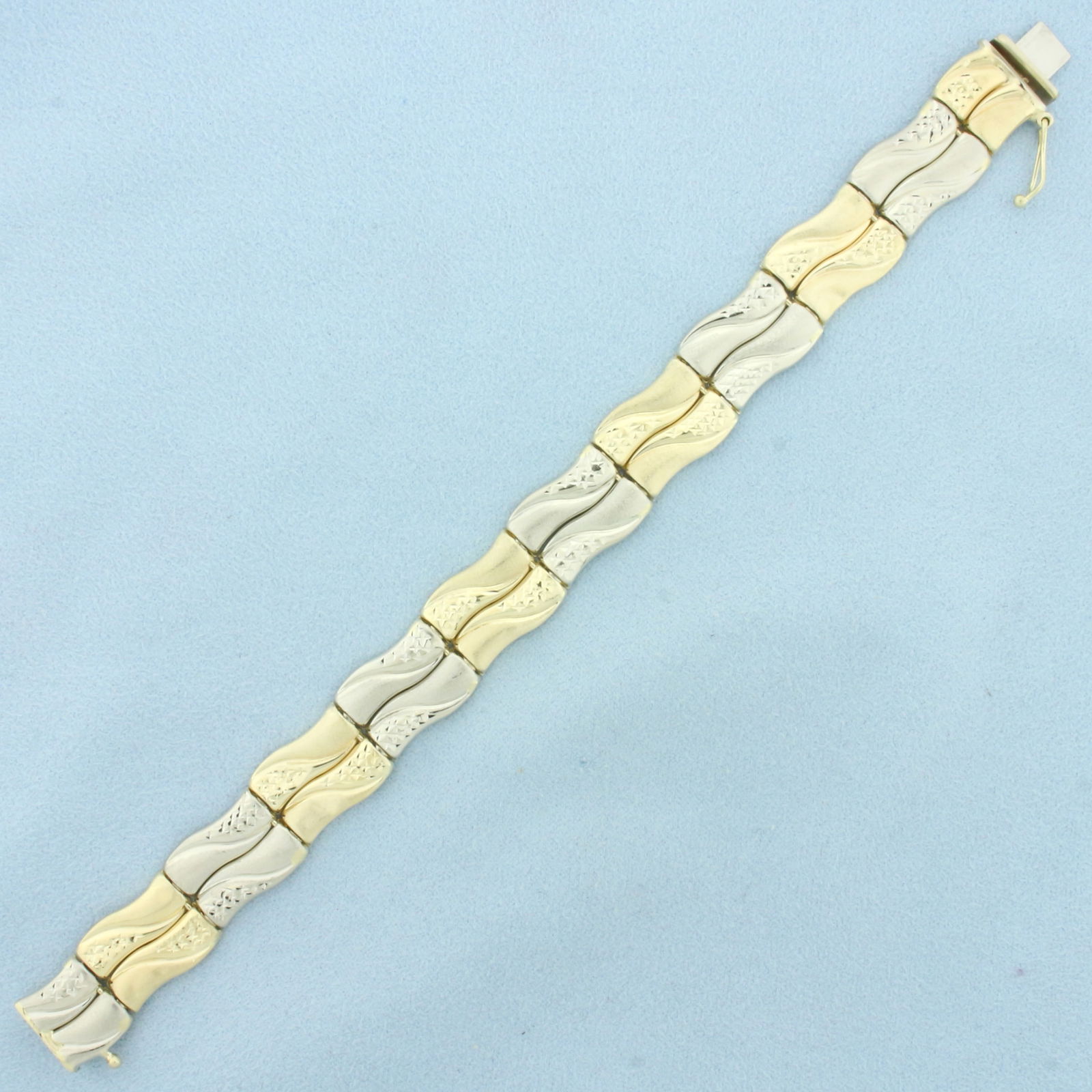 Diamond Cut Wave Design Bar Bracelet in 14k Yellow and White Gold: In 14k yellow and white gold. 7 1/8 inches long and 1/2 inches wide. Satin and diamond cut details. Minor indentation, not noticeable. Concealed slide clasp with safety latch. 15.3g.