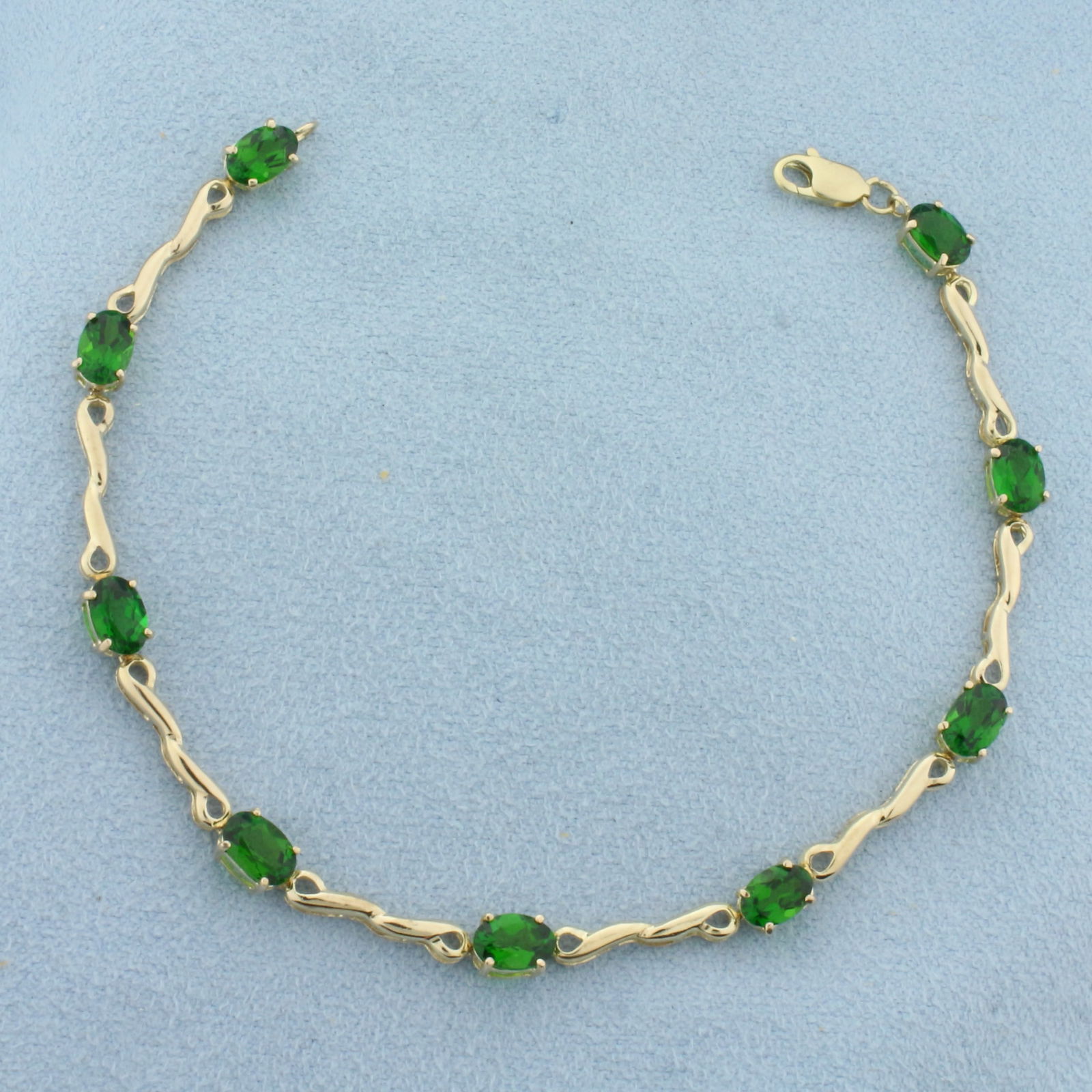 Green Garnet Tennis Bracelet in 10K Yellow Gold: In 10k yellow gold. Measures 7.13 inches long. Contains 9 high quality natural 6mm Green Garnet Gemstones with vibrant color and excellent clarity. Lobster clasp. 4.3g.