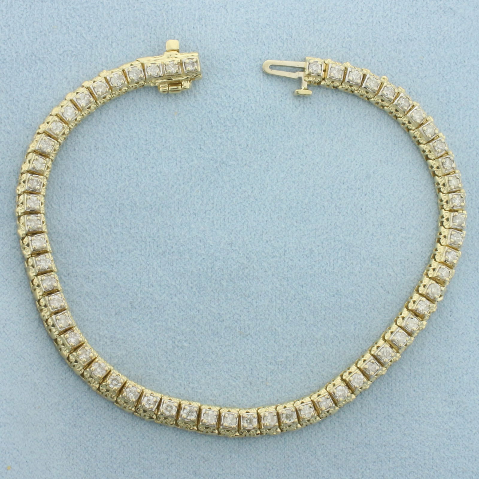 Diamond Tennis Bracelet in 14k Yellow Gold: In 14k Yellow Gold. Contains fifty-eight high quality diamonds, 2ct TW, I color/I clarity. 7 3/8 inches long. 5mm wide. Concealed slide clasp with underswing safety latch. 14.1g.