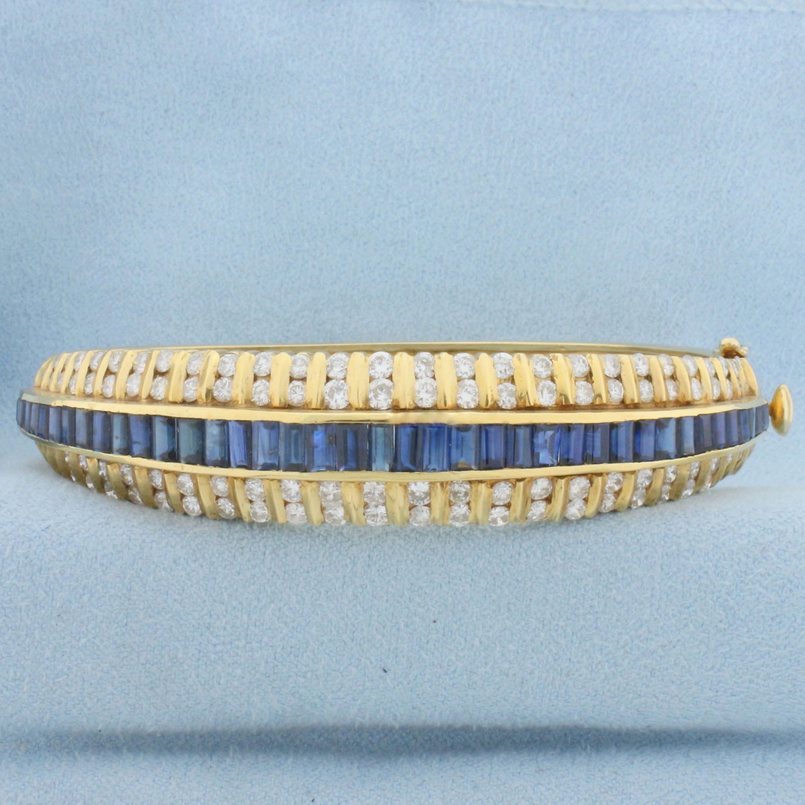 Designer 5ct Sapphire and Diamond Bangle Bracelet in 18k Yellow Gold: In 18k yellow gold. Contains 3ct TW of high quality round brilliant diamonds, VS clarity/G color. Also contains forty baguette shaped high quality natural sapphires ranging from 2.5mm to 4mm long each