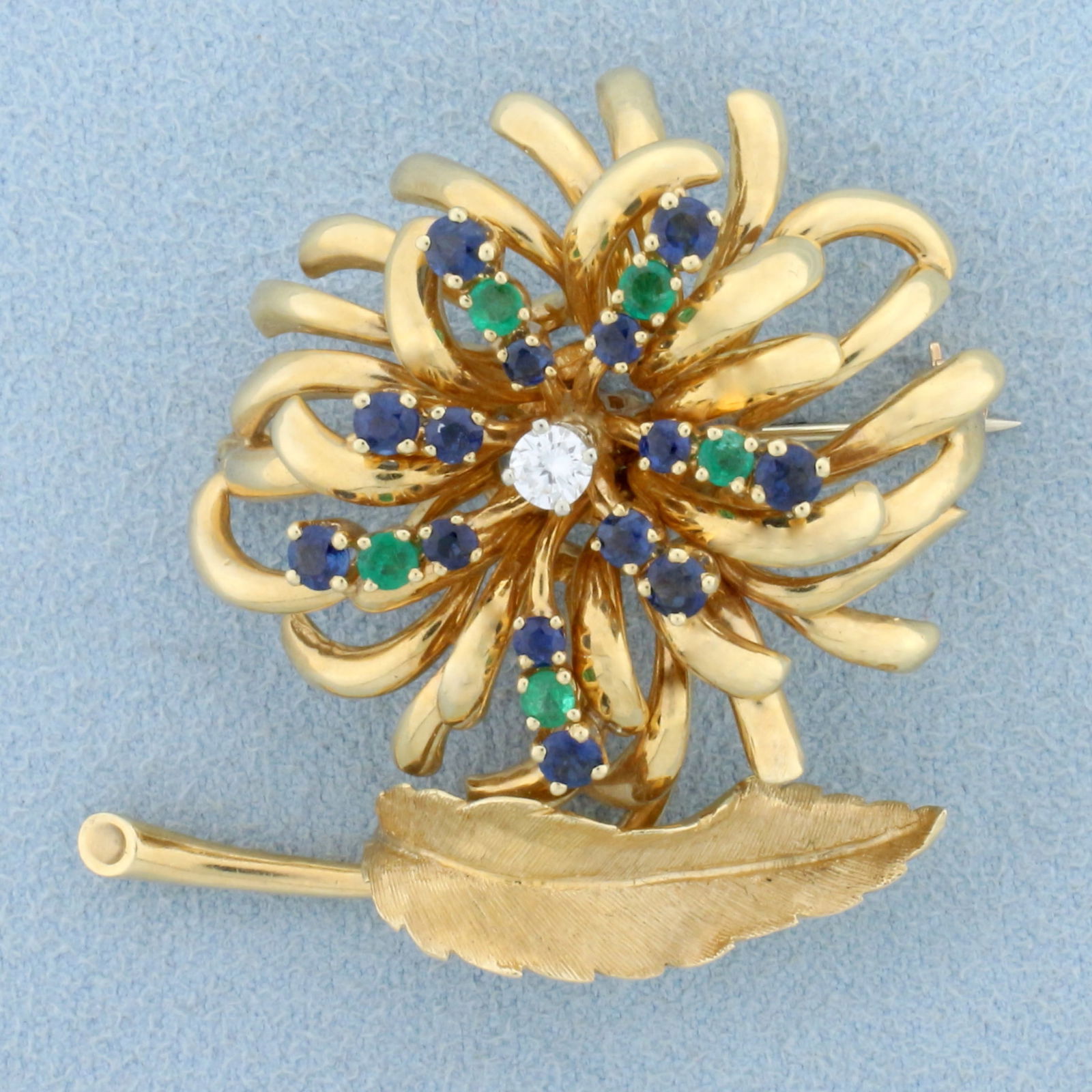 Vintage Designer Dan Frere Emerald, Sapphire, and Diamond Feather and Flower Design Pin Brooch in: In 14k yellow gold. Containing five high quality natural 2.5mm Emerald and Sapphire gemstones with vibrant color and excellent clarity. Center diamond is very high quality .15ct round brilliant, VS