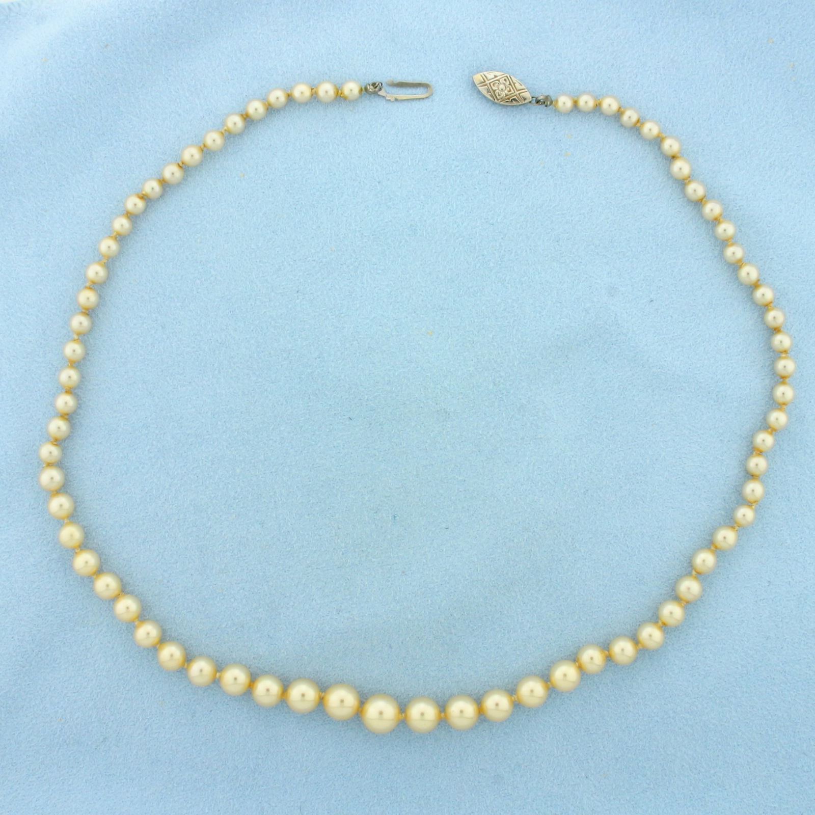 Vintage Graduated Pearl Strand Necklace in 10k White Gold: 10k White Gold clasp. Contains 3.8-7.7mm high quality Cultured Akoya Pearls with creamy golden undertone and high luster. 16 inches long. Hand knotted. Decorative filigree locking clasp.