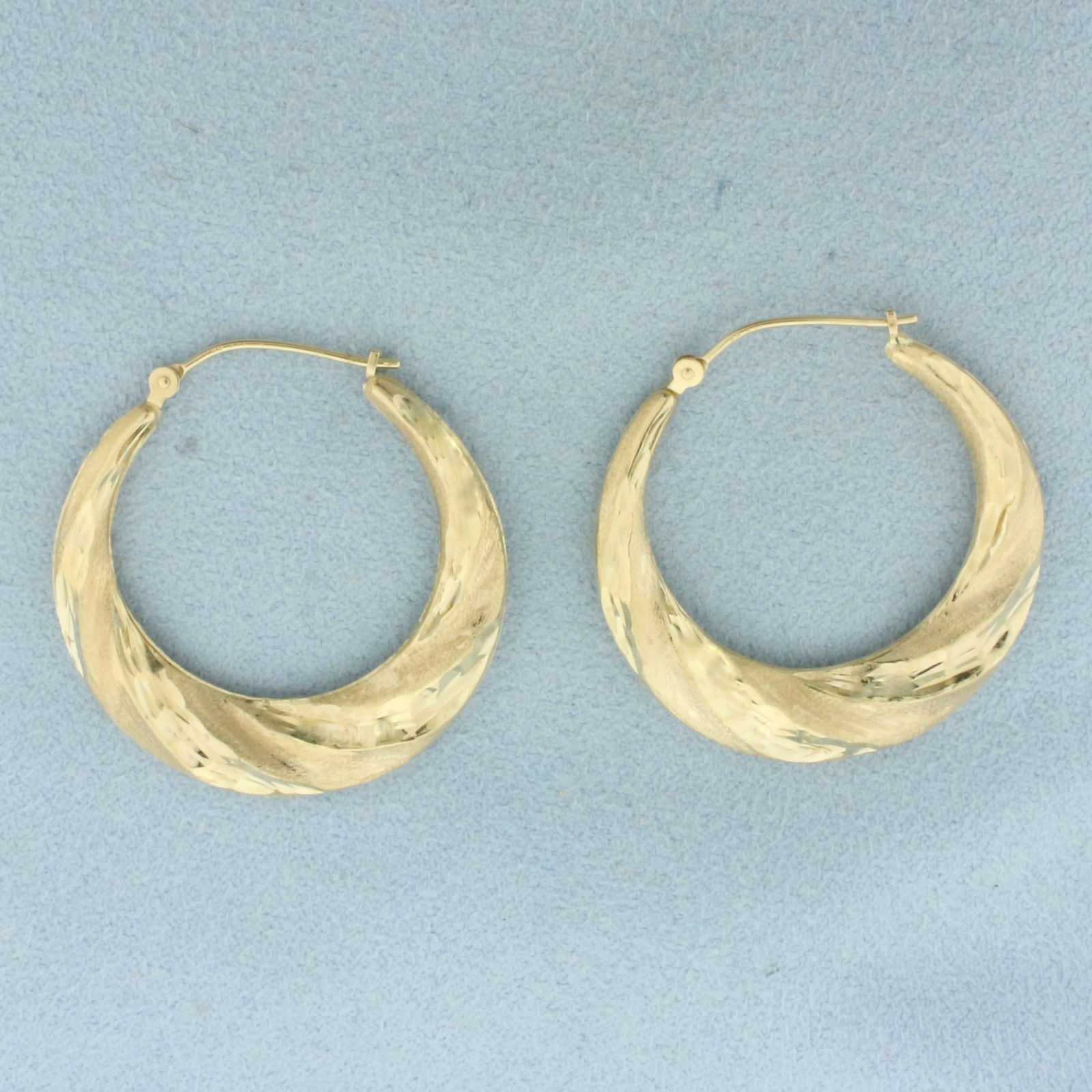 Diamond Cut Twisting Hoop Earrings in 14k Yellow Gold: In 14k Yellow Gold. 1 1/4 inch long. 3.3mm thick. Hinged backs. 2.7g.