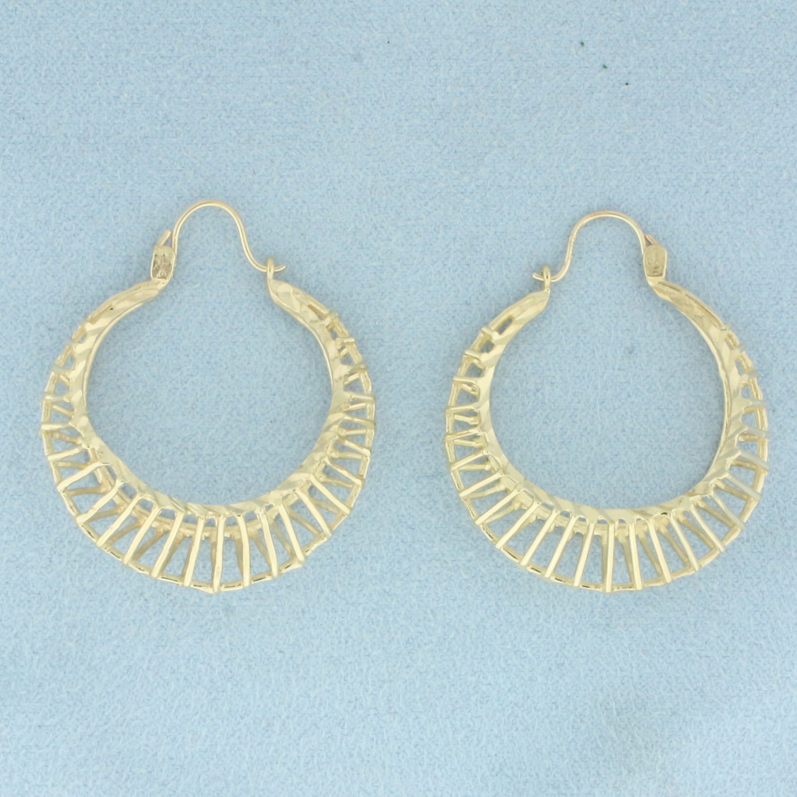 Diamond Cut Cage Hoop Earrings in 10k Yellow Gold: In 10k Yellow Gold. 1 3/8 inch long. 1 1/4 inch wide. Locking hoop hook closure. 6.9g.