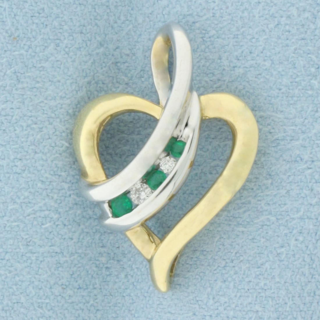 Emerald and Diamond Heart Pendant in 10k Yellow and White Gold: In 10k Yellow and White Gold. Contains one 1.5mm, one 1.75mm, and one 2mm high quality natural Emerald gemstones, with vibrant color. Also contains one .01ct and one .02ct high quality diamonds, SI