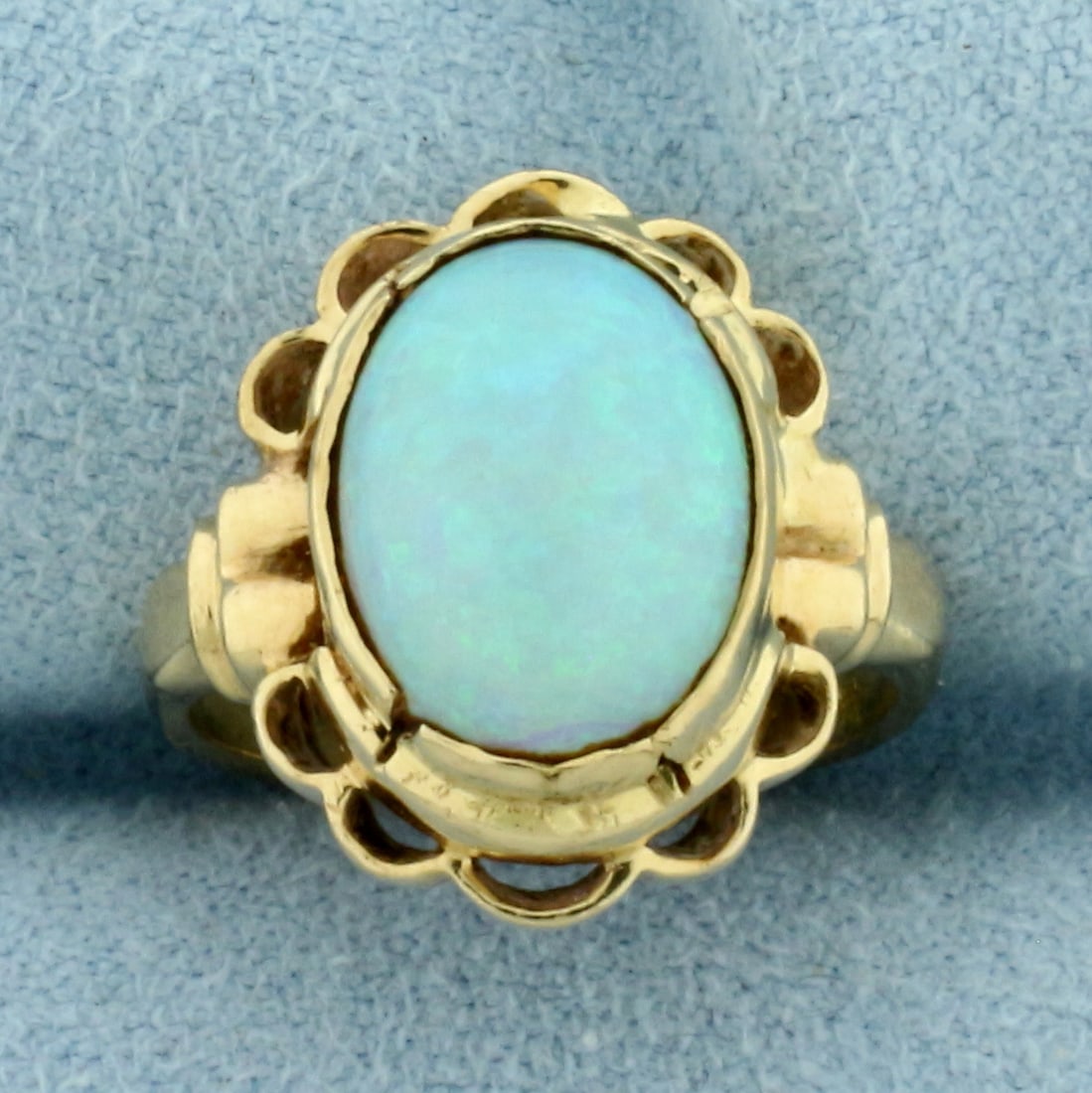 Opal Solitaire Ring in 14k Yellow Gold: In 14k Yellow Gold. Contains one 12x10mm high quality natural Opal gemstone with excellent play of color, flashes of purple, blue, orange, and red. 16.9mm wide at center. Size 4.5. 4.0g.