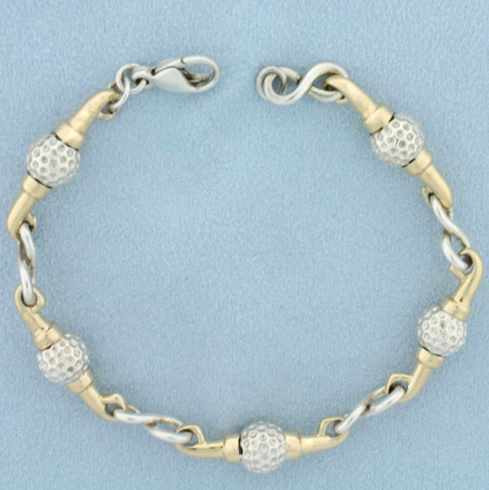 Golf Ball Link Bracelet in 14K Yellow Gold and Sterling Silver: In 14K Yellow Gold and Sterling Silver. 7 1/2 inches long, 7.9mm wide. Lobster clasp. 26.6g.