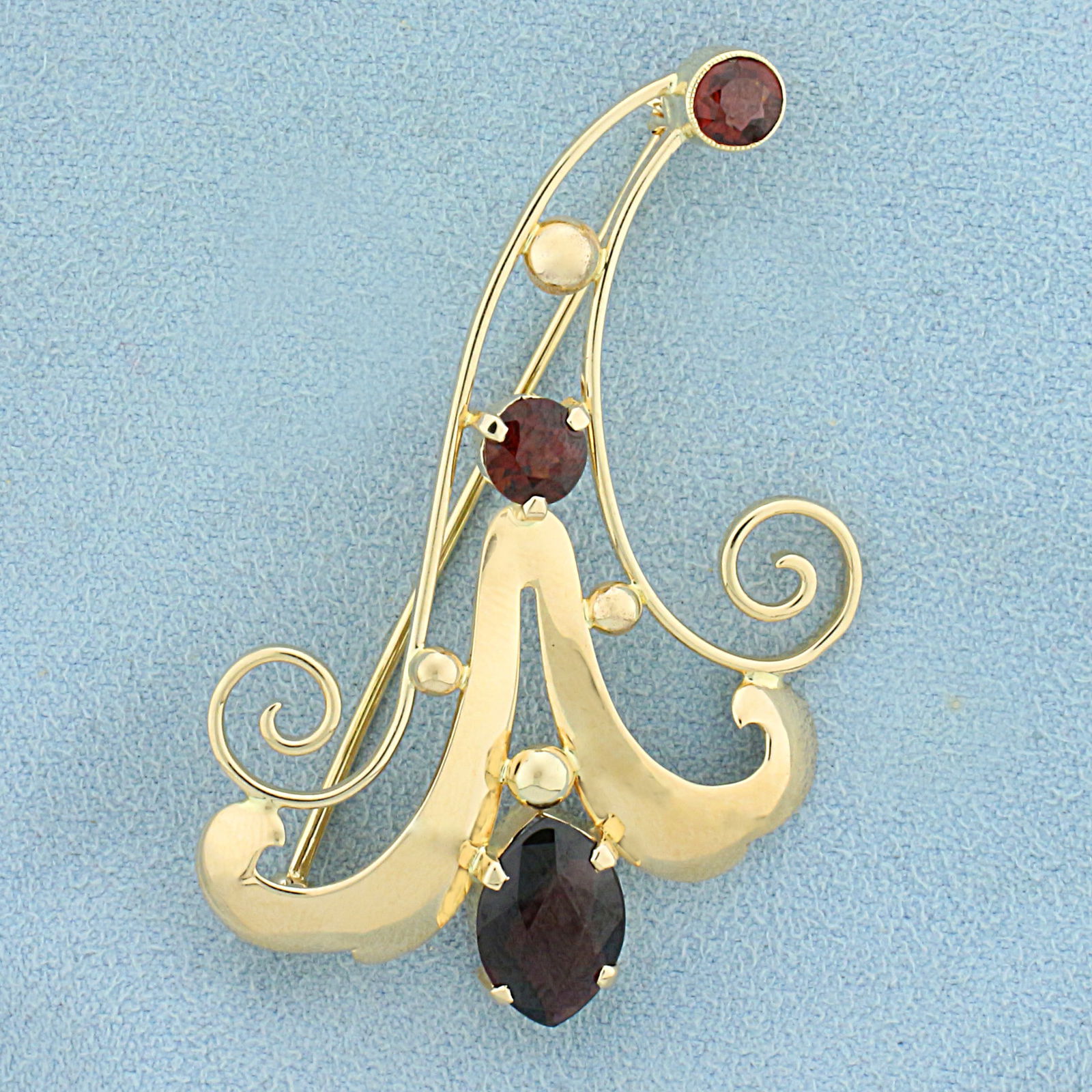 Vintage Garnet Pin in 14K Yellow Gold: In 14K Yellow Gold. Contains one 12 x 8mm marquise, one 5.5mm round, and one 4.5mm round high quality natural Garnet gemstones with intense color and excellent clarity. 2 inches long. 1 1/4 inch wide.