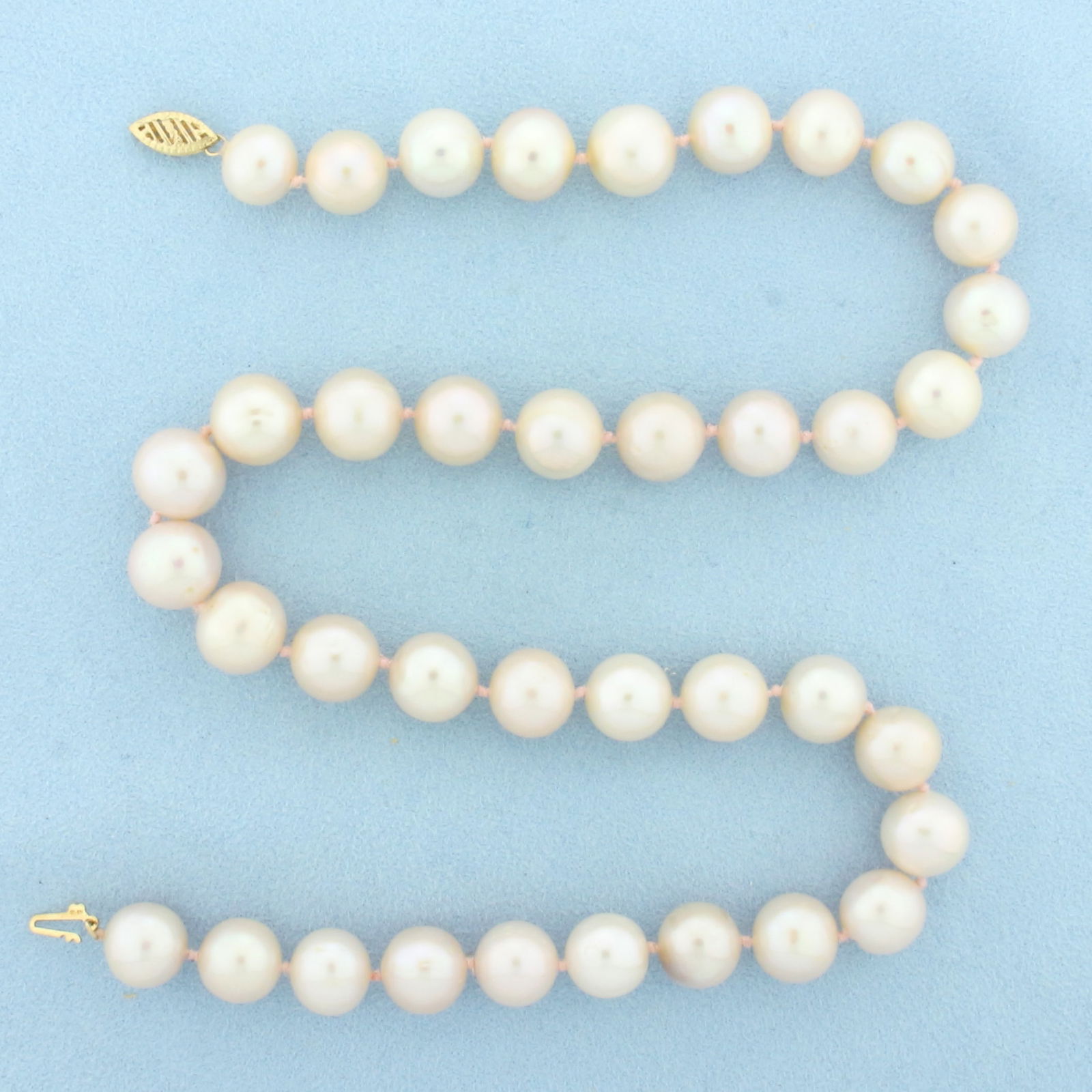 Pink Cultured Akoya Pearl Strand Necklace in 14k Yellow Gold: 14k Yellow Gold clasp. 18 1/4 inches long. Contains 11mm high quality Akoya Pearls with high luster and beautiful pink undertone. Hand knotted on pink thread. Decorative filigree clasp. 67.0g.