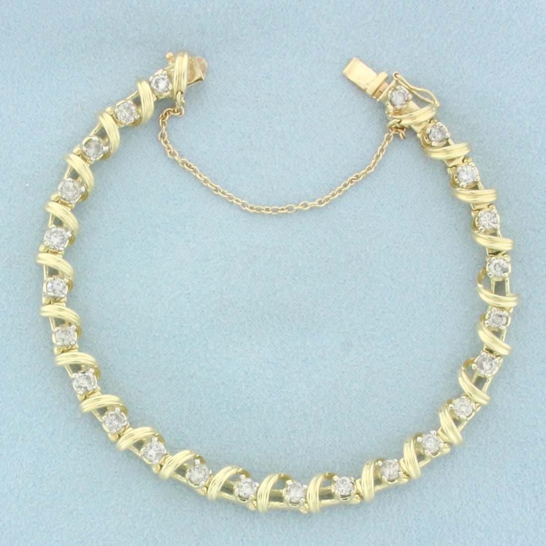 Spiral Ribbon Design Diamond Tennis Bracelet in 14k Yellow Gold: In 14k yellow gold. Contains 24 high quality diamonds, 2.5ct TW, H color/I clarity. Concealed slide clasp with safety chain and safety latch. 7 1/4 inches long. 6mm wide. 16.8g.
