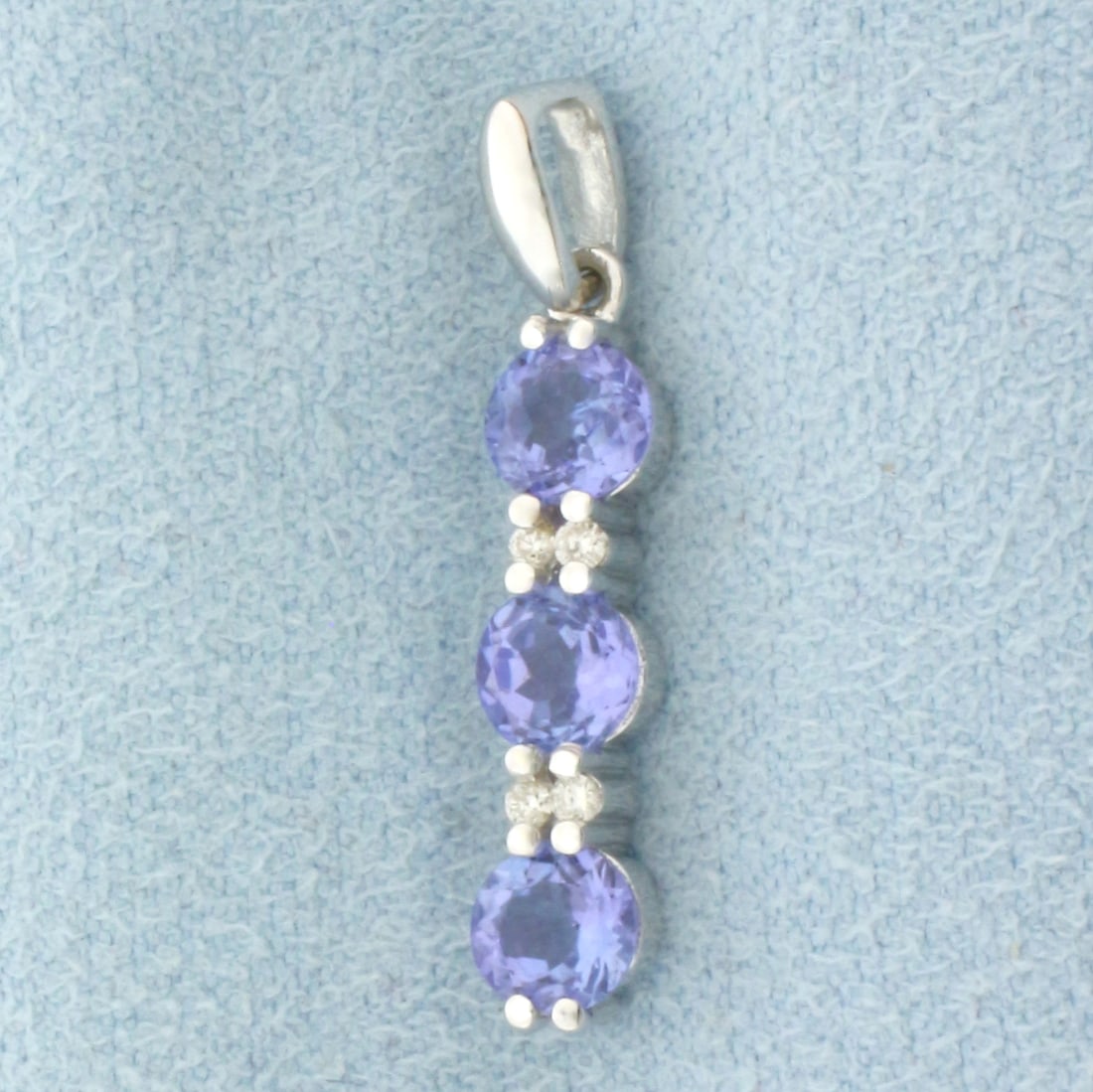 Tanzanite and Diamond Pendant in 14k White Gold: In 14k White Gold. Contains three 4.5mm high quality natural Tanzanite gemstones, approximately 1ct TW, with intense color and excellent clarity. Also contains four 1/2pt high quality diamonds. 1 inch