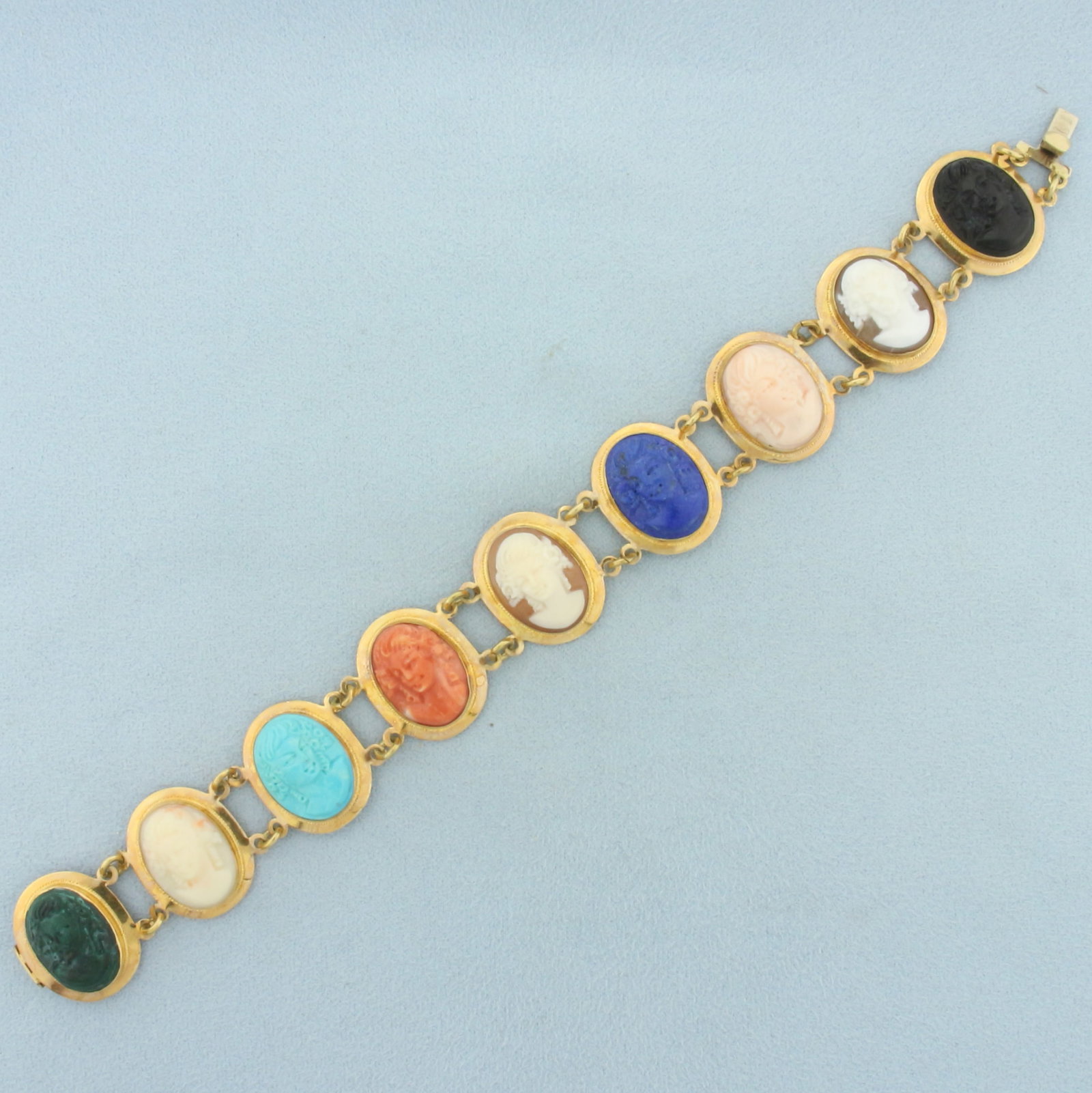 Multi Gem Hand Carved Cameo Bracelet in 18k Yellow Gold: In 18k yellow gold. 7 1/4 inches long by 3/4 inches wide. Contains nine 16 by 12mm hand carved cameos in turquoise, shell, Lapis lazuli, coral, onyx, and jade. Concealed slide clasp. 23.7g.