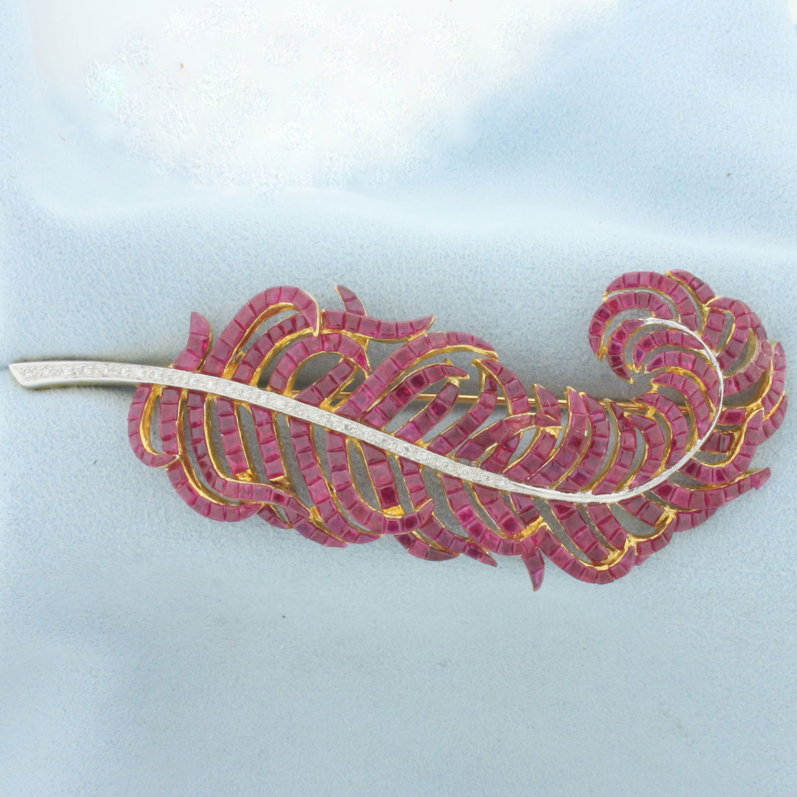 Ruby and Diamond Feather Brooch in 18k Yellow Gold: In 18k yellow gold. Contains 306 ruby gemstones, approximately 15cts TW, with vibrant color and excellent clarity. Accented by 27 diamonds, 1/4ct TW, VS clarity/G color. 3.5 inches long x 1.5