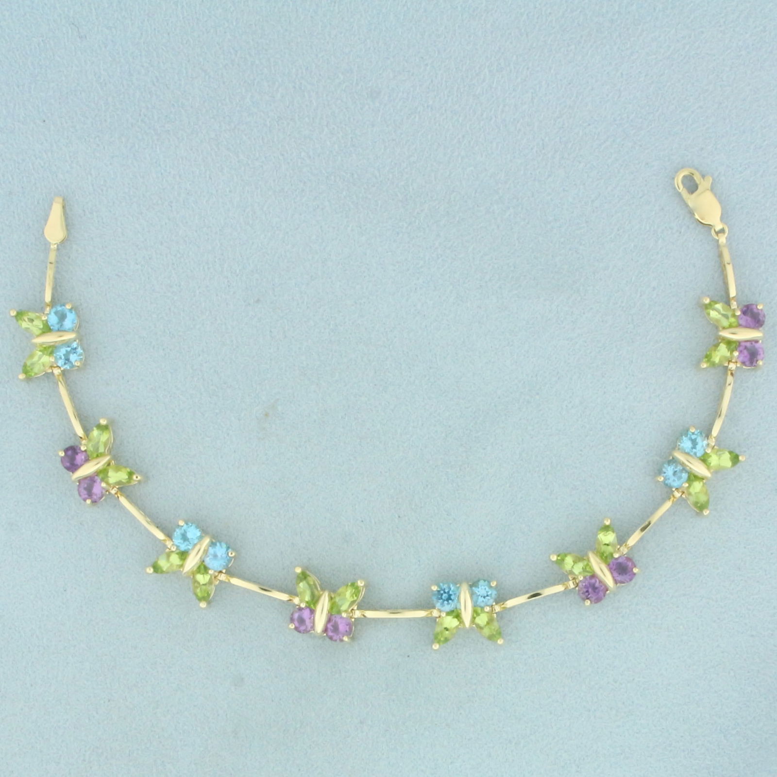 Rainbow Gemstone Butterfly Bracelet in 14k Yellow Gold: In 14k yellow gold. Contains 16 high quality natural 6mm peridot gemstones, 8 high quality natural 4mm blue topaz gemstones and 8 high quality natural 4mm amethyst gemstones, all with vibrant color an