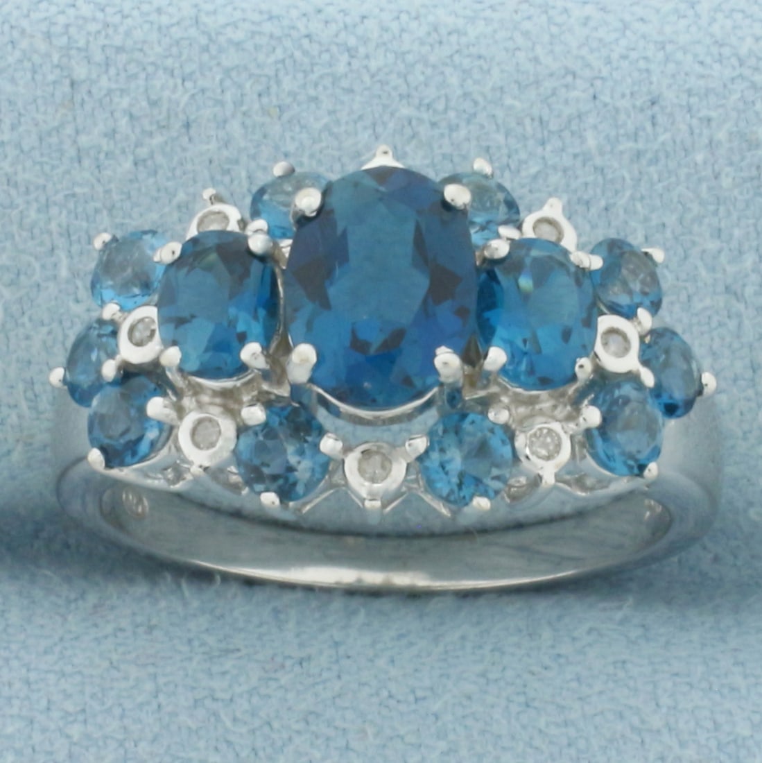 London Blue Topaz and Diamond Ring in 10k White Gold: In 10k White Gold. Contains one 8x6mm oval, two 5x4mm oval, and ten 3mm round natural London Blue Topaz gemstones with intense color and excellent clarity. Also contains eight high quality 1/2pt diamo