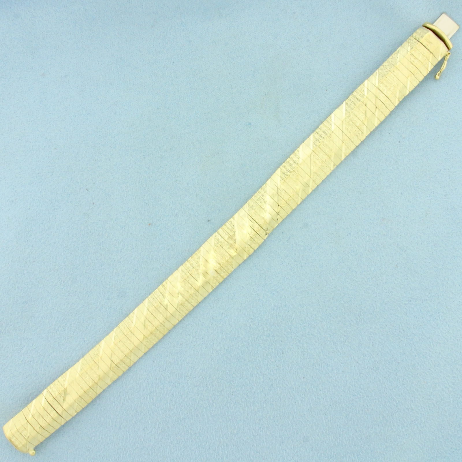 Italian Diamond Cut Striped Wide Omega Bracelet in 14k Yellow Gold: In 14k Yellow Gold. 7 1/8 inches long. 1/2 inch wide. Italian made. Concealed slide clasp with safety latch. 20.8g.