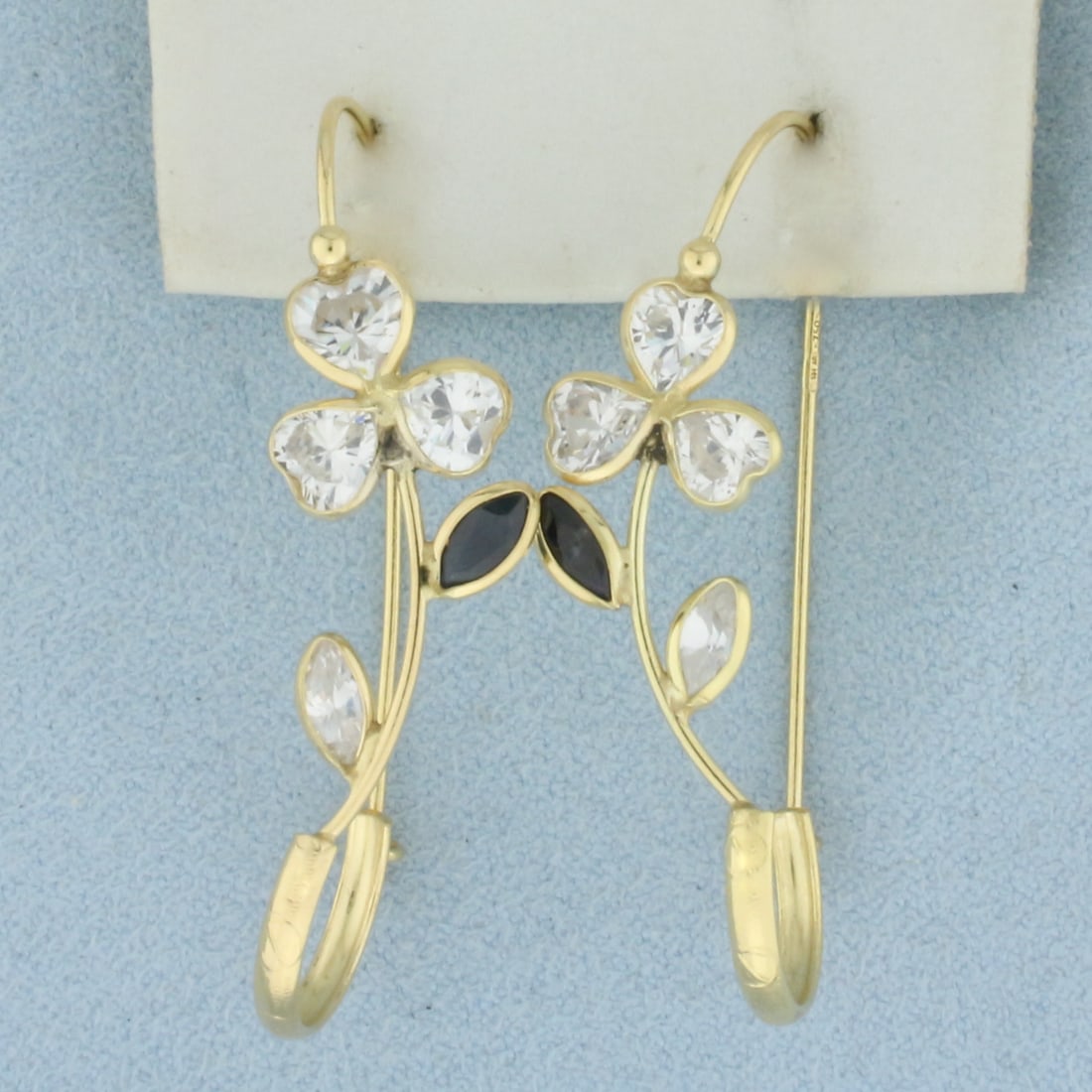 Sapphire Flower Drop Earrings in 18k Yellow Gold: In 18k Yellow Gold. Contains two 6mm high quality natural Sapphire gemstone with intense color. Also contains fourteen high quality CZ gemstones with excellent cut and clarity for added brilliance. 1