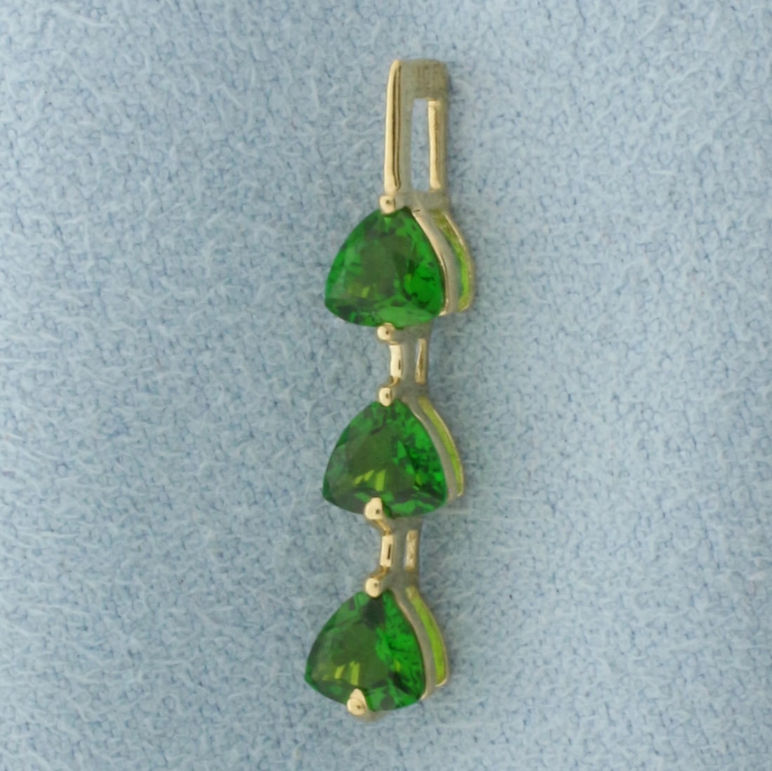 Green Garnet Pendant in 10k Yellow Gold: In 10k yellow gold. 1" long. Contains three 4.5mm high quality natural trillion cut Green Garnet gemstones with vibrant color and excellent clarity. 0.7g