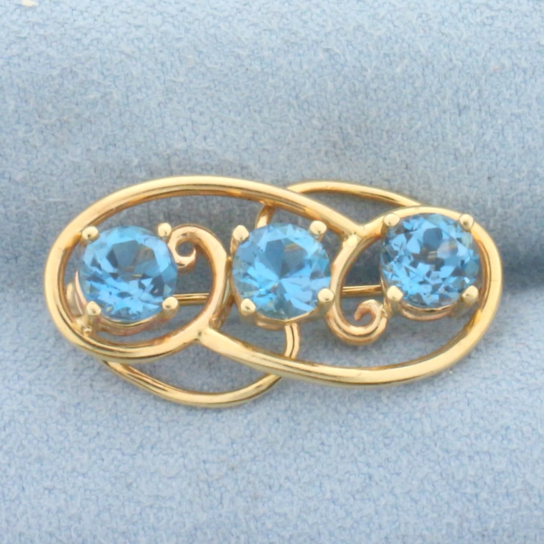 Vintage Swiss Blue Topaz Brooch in 14k Yellow Gold: In 14k yellow gold. Contains three 6mm high quality natural swiss blue topaz gemstones with eclectic blue color and excellent clarity. 1 1/8 inches long, 5/8 of an inch wide. Hinged pin with lock. 4.7