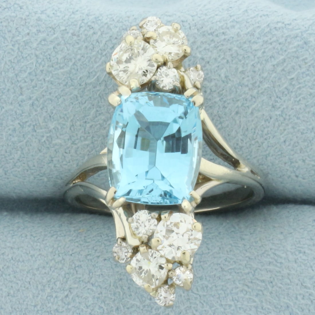 Vintage Blue Topaz and Diamond Retro Era Cocktail Ring in 14k White Gold.: In 14k white gold. Contains one 11mm by 9mm elongated cushion cut Swiss blue topaz gemstone with electric blue color and excellent clarity. Accented by twelve high quality diamonds ranging from 1/3ct