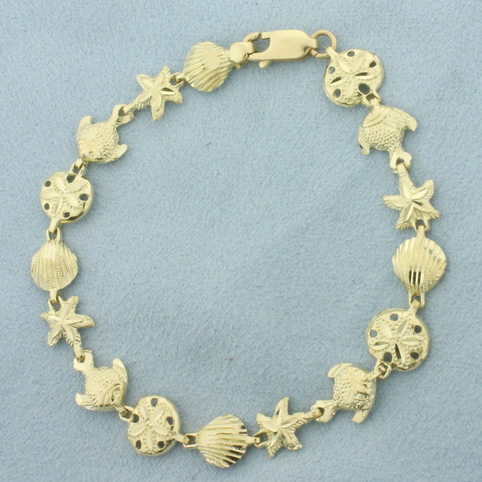 Sealife Seashell, Fish, Starfish, and Sand Dollar Bracelet in 14k Yellow Gold: In 14k Yellow Gold. 7 1/8 inches long. 3/8 inch wide. Lobster clasp. Diamond cut for added sparkle. 7.4g.