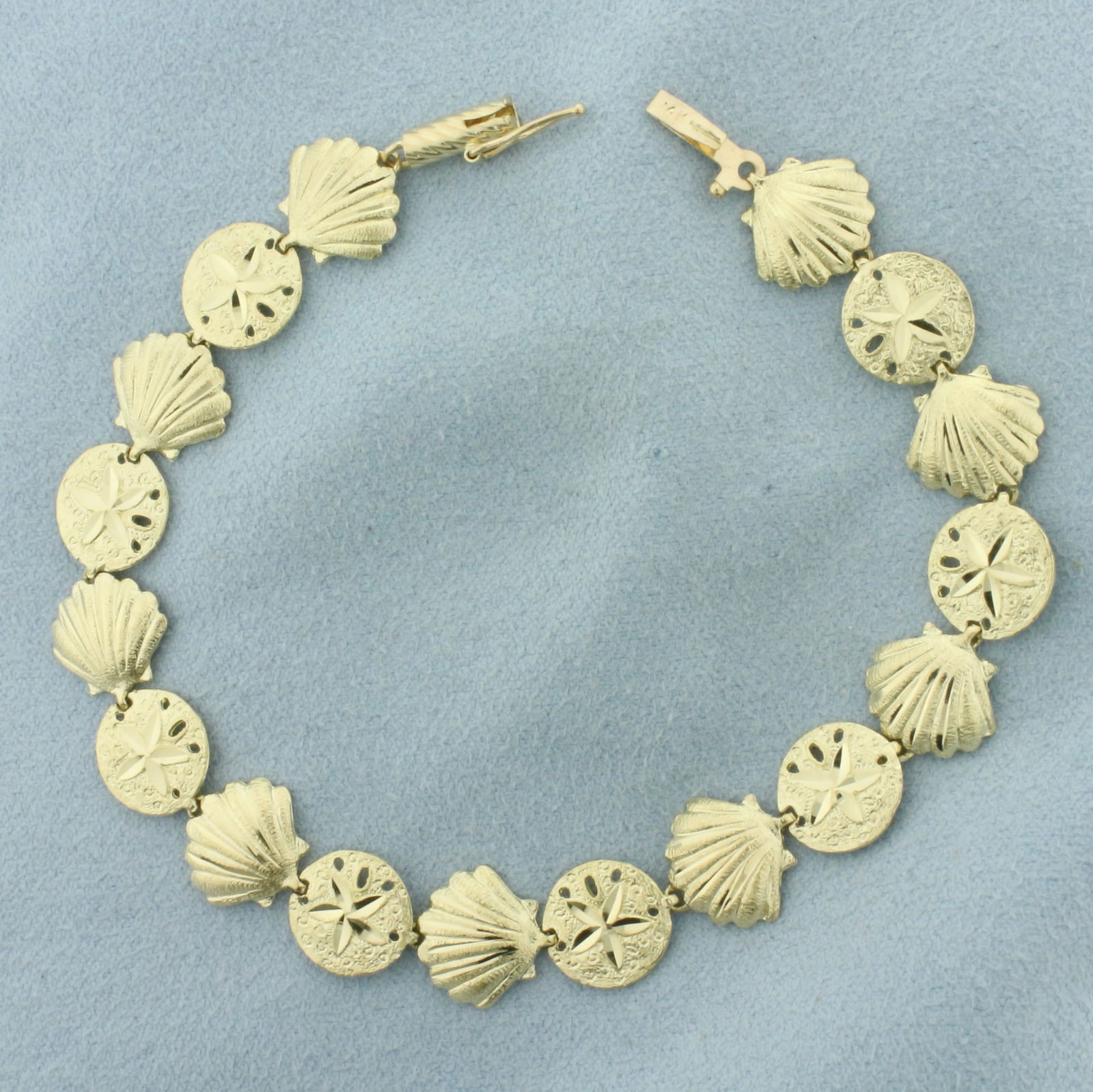 Sea Life Seashell and Sand Dollar Bracelet in 14k Yellow Gold: In 14k Yellow Gold. 7 1/8 inches long. 3/8 inch wide. Diamond cut for added sparkle. Barrel clasp with safety latch. 7.0g.