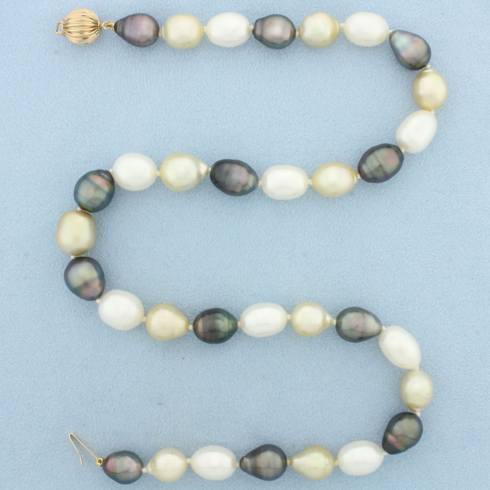 Tahitian and South Sea Baroque Cultured Pearl Strand Necklace in 14k Yellow Gold: 14k Yellow Gold Clasp. Contains 33 black/silver Tahitian and golden South Sea Cultured Pearls with high luster, 10 to 11mm each. 17.5 inches long. Hand knotted. Decorative scalloped gold bead clasp.
