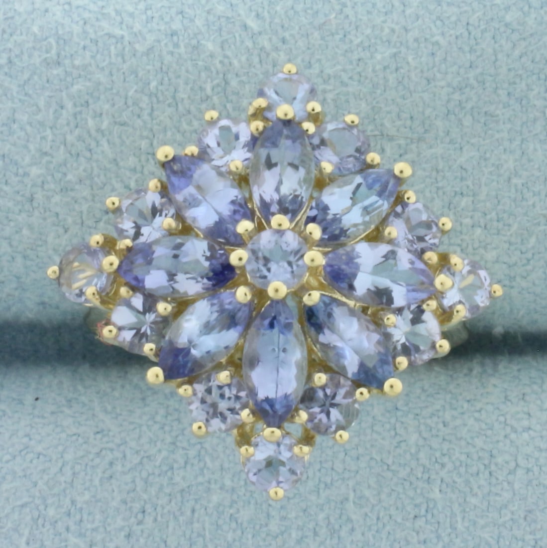 Tanzanite Flower Ring in 10k Yellow Gold: In 10k Yellow Gold. Contains thirteen 3mm round and eight 6mm marquise high quality natural Tanzanite gemstones with bright color and excellent clarity. Approximately 3ct TW. 21.5mm wide a top of ring