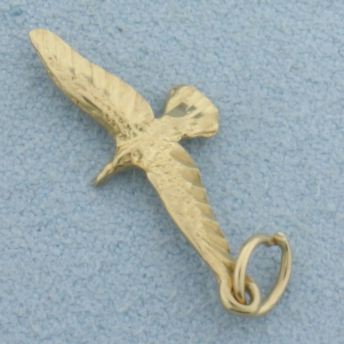 Flying Hawk Bird Charm in 14k Yellow Gold: In 14k Yellow Gold. 1 1/8 inches long including jump ring. 3/8 inch wide. 0.7g.