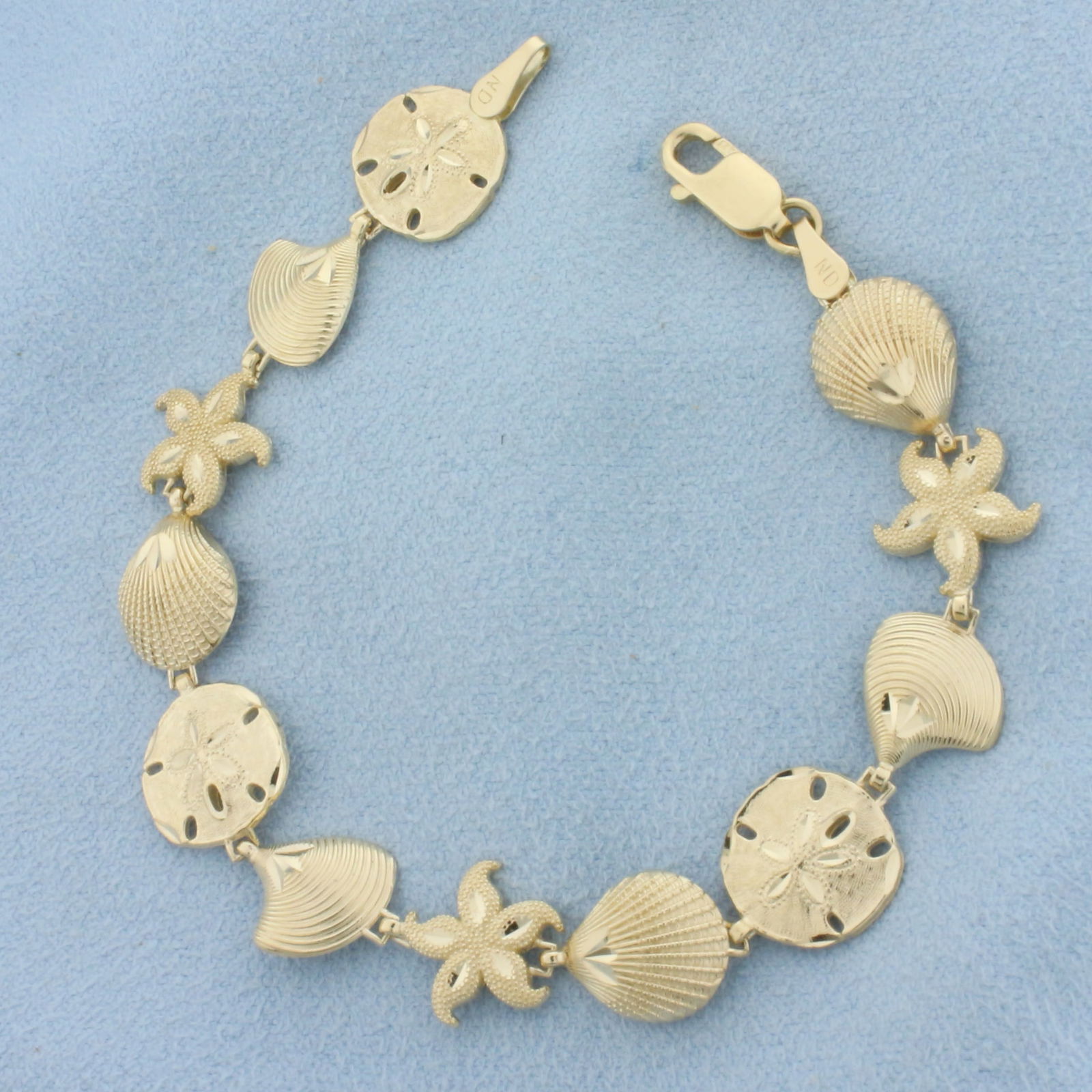Sea Life Sand Dollar Seashell Starfish Bracelet in 14k Yellow Gold: In 14k Yellow Gold. 6 3/4 inches long. 10mm wide. Lobster clasp. 7.4g.